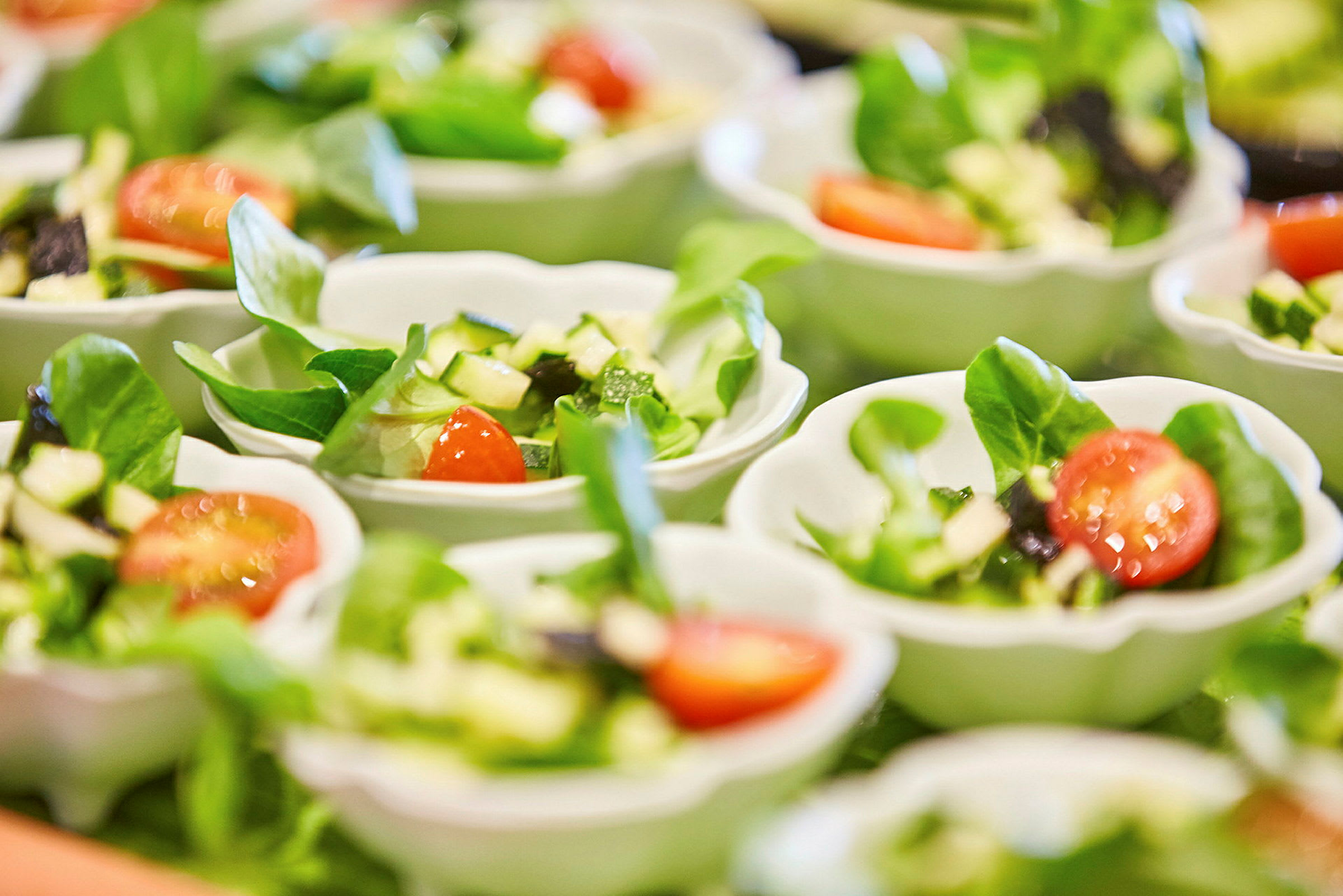 Små skålar innehåller sallad, med bladgrönsaker och tomathalvor. (AI-genererad text)