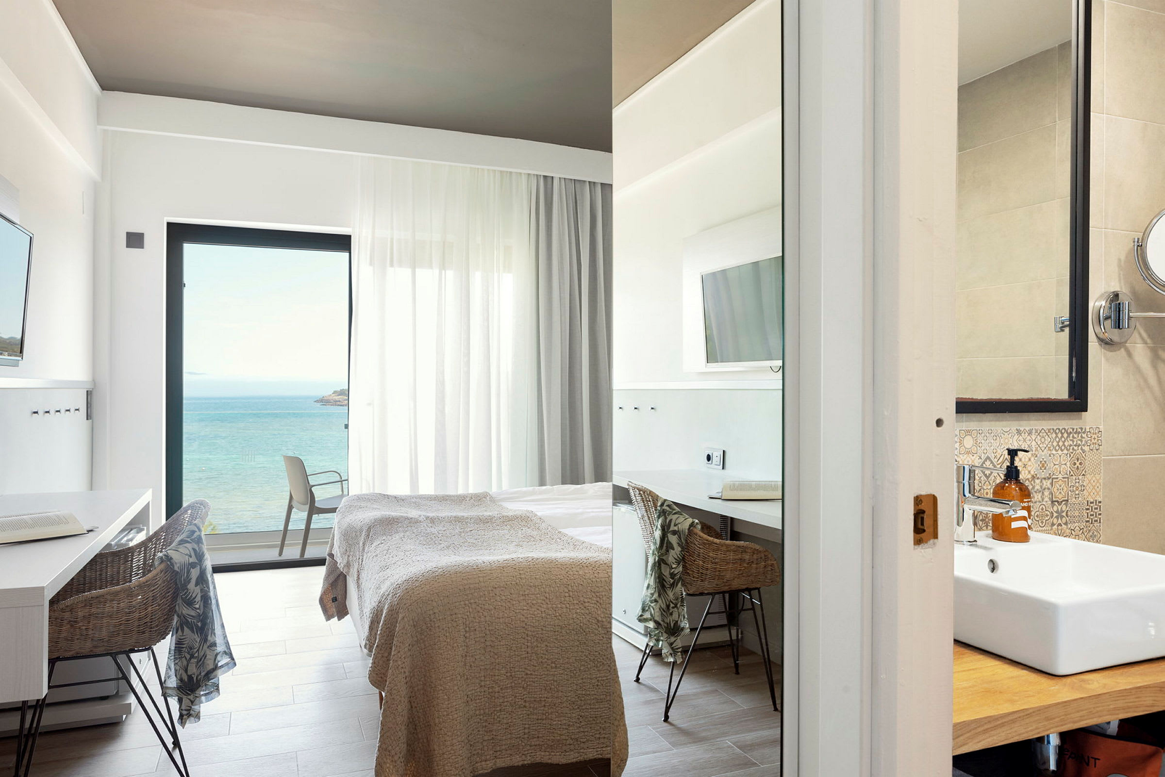 Modernt hotellrum med havsutsikt, säng och arbetsområde samt del av badrum. (AI-genererad text)