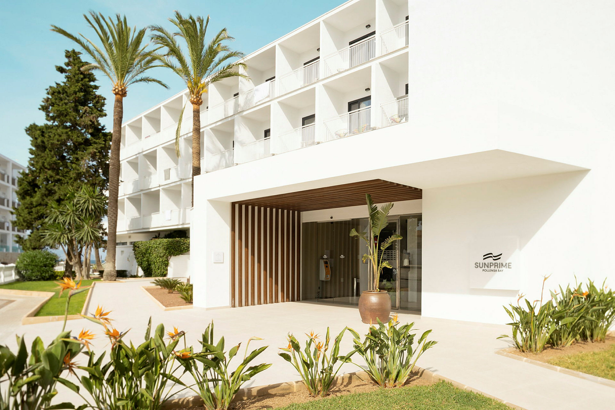 Entré till hotell Sunprime med omgivande växter och palmer. (AI-genererad text)