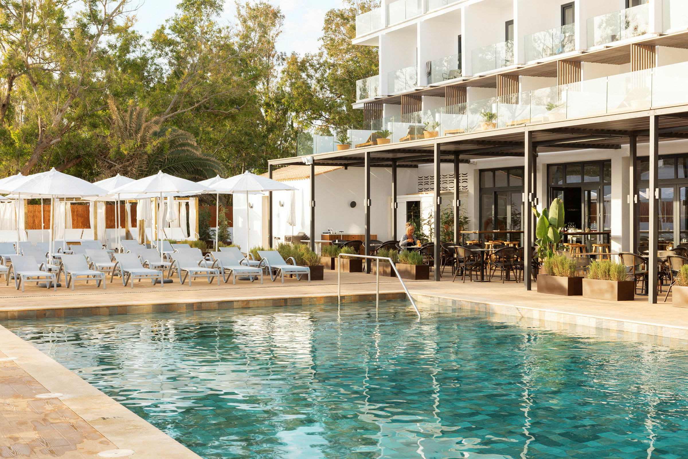 Utomhuspool omgiven av solstolar och parasoller vid ett hotell. (AI-genererad text)