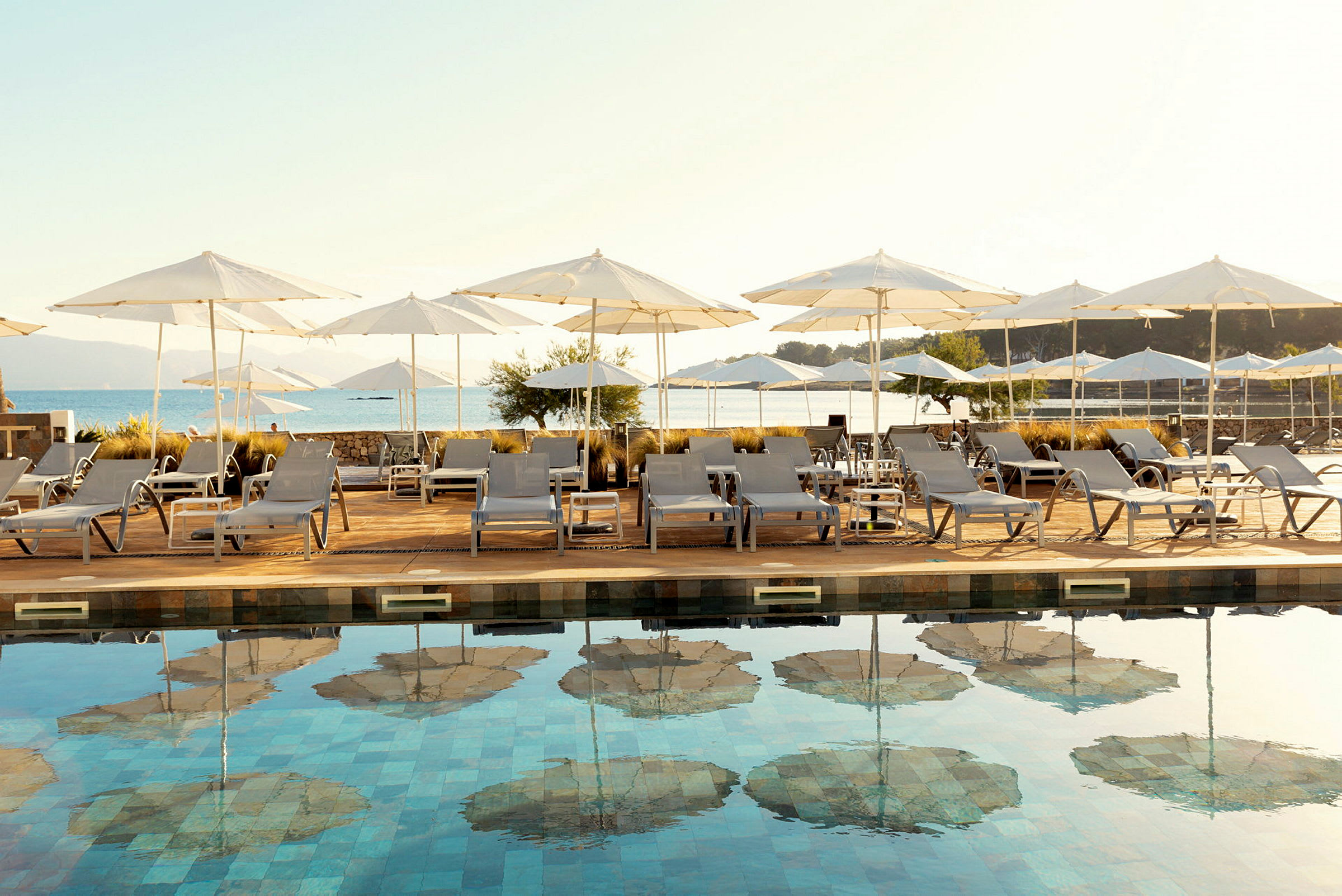 Solstolar och parasoller vid en pool med utsikt över havet. (AI-genererad text)