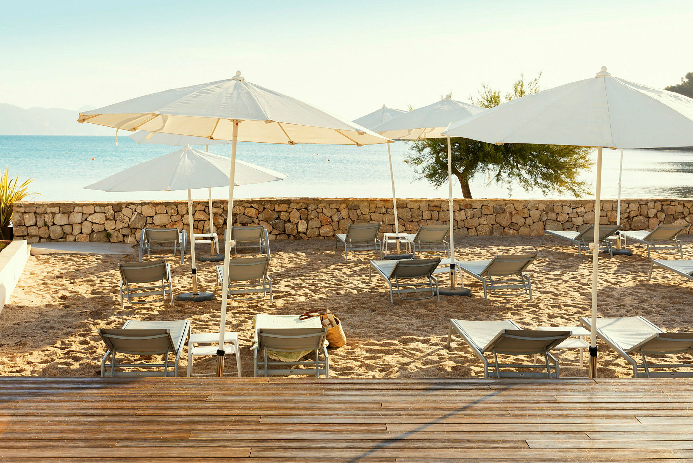 Solstolar och parasoller på en sandstrand, med havet i bakgrunden. (AI-genererad text)