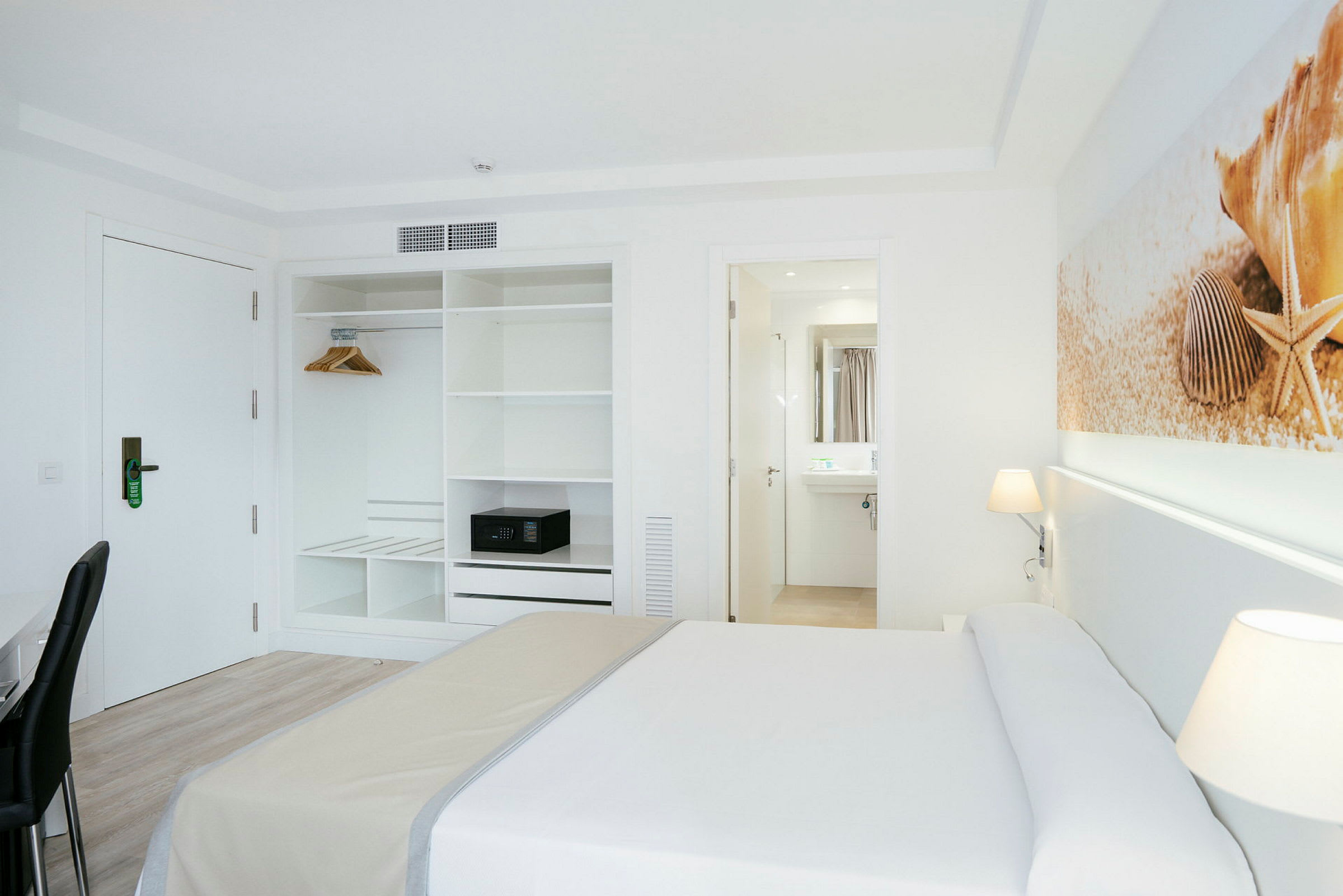 Hotellrum med säng, garderob och ingång till ett badrum. (AI-genererad text)