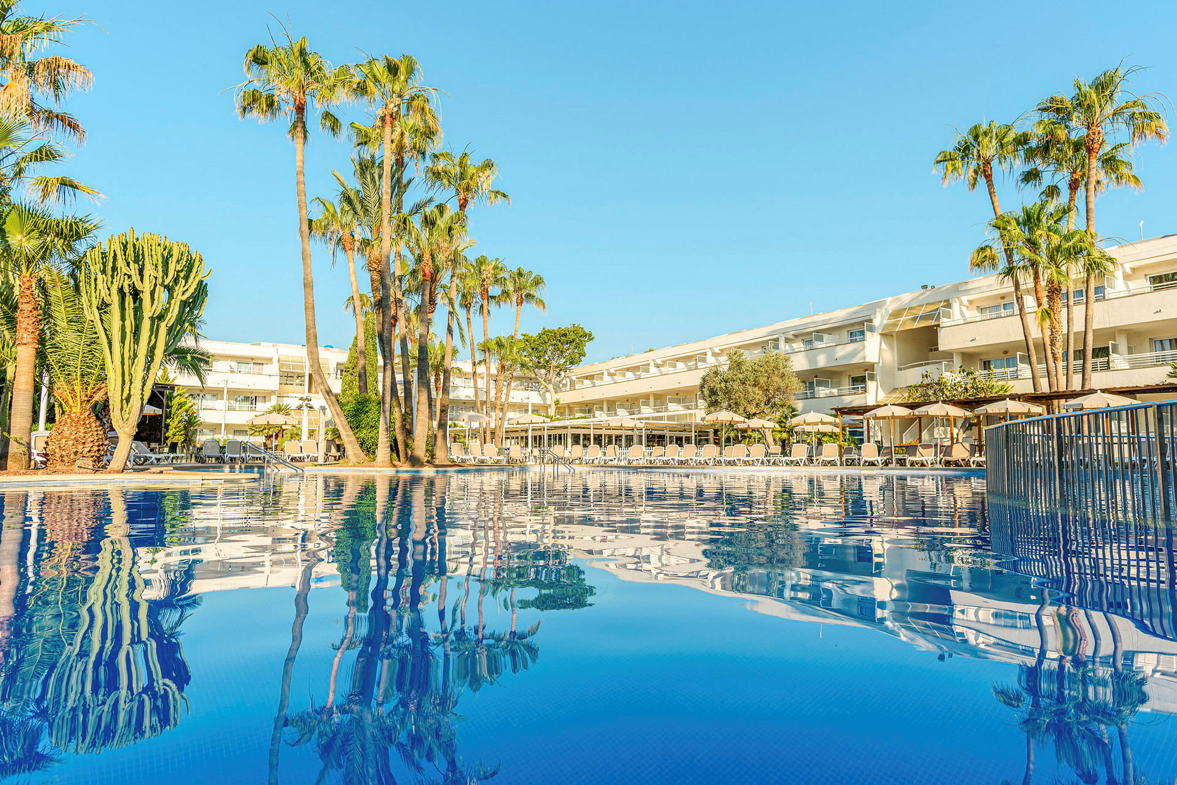 Bild av ett hotell med palmer vid en pool. (AI-genererad text)