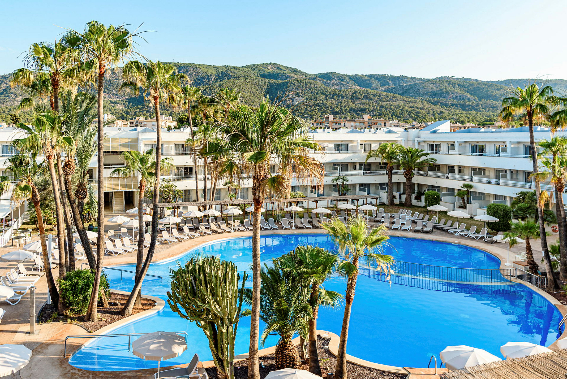 Poolområde vid hotell med omgivande palmer och solstolar. (AI-genererad text)