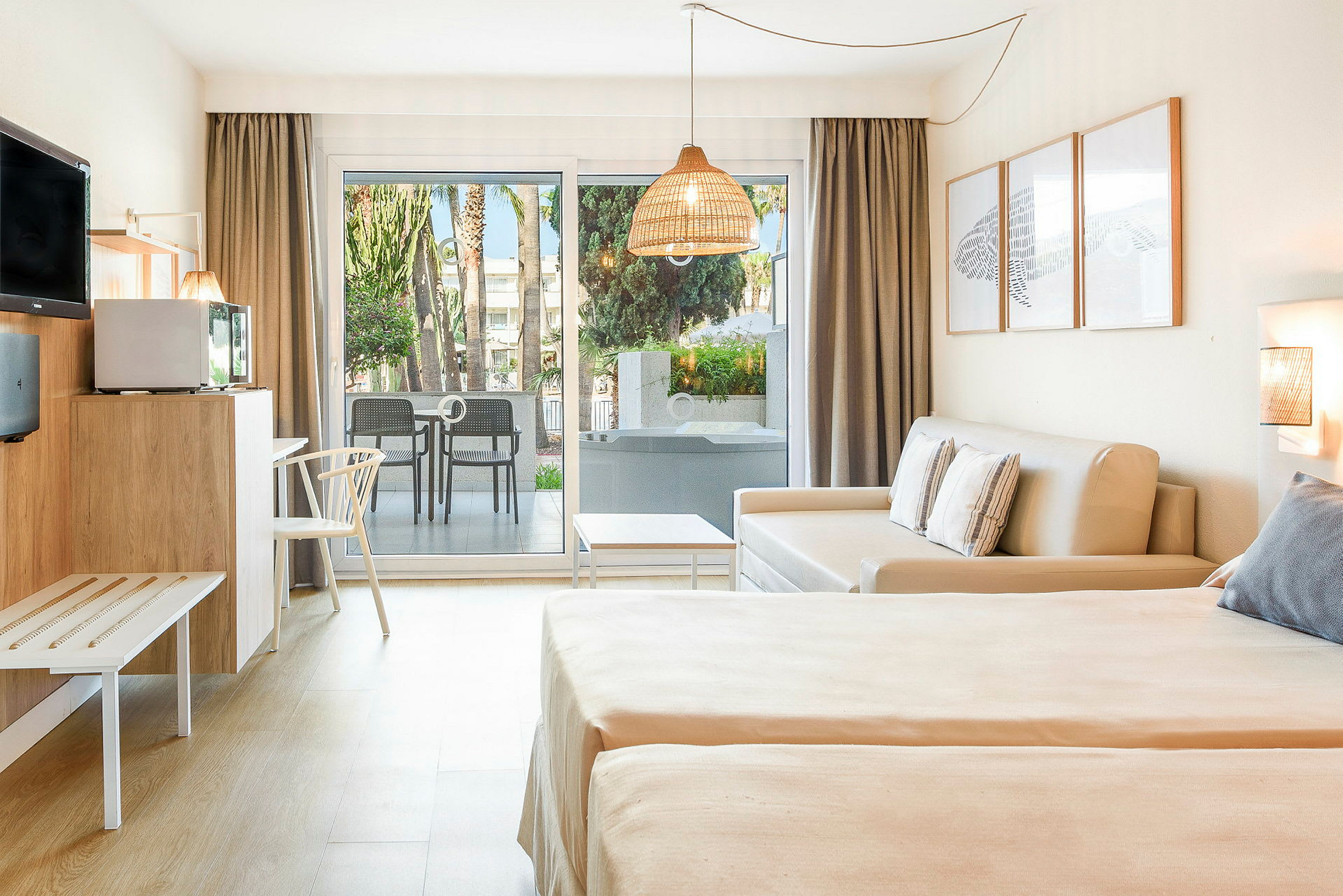 Ett hotellrum med ljus inredning, en bäddsoffa, två sängar och en terrass med utsikt över grönska. (AI-genererad text)