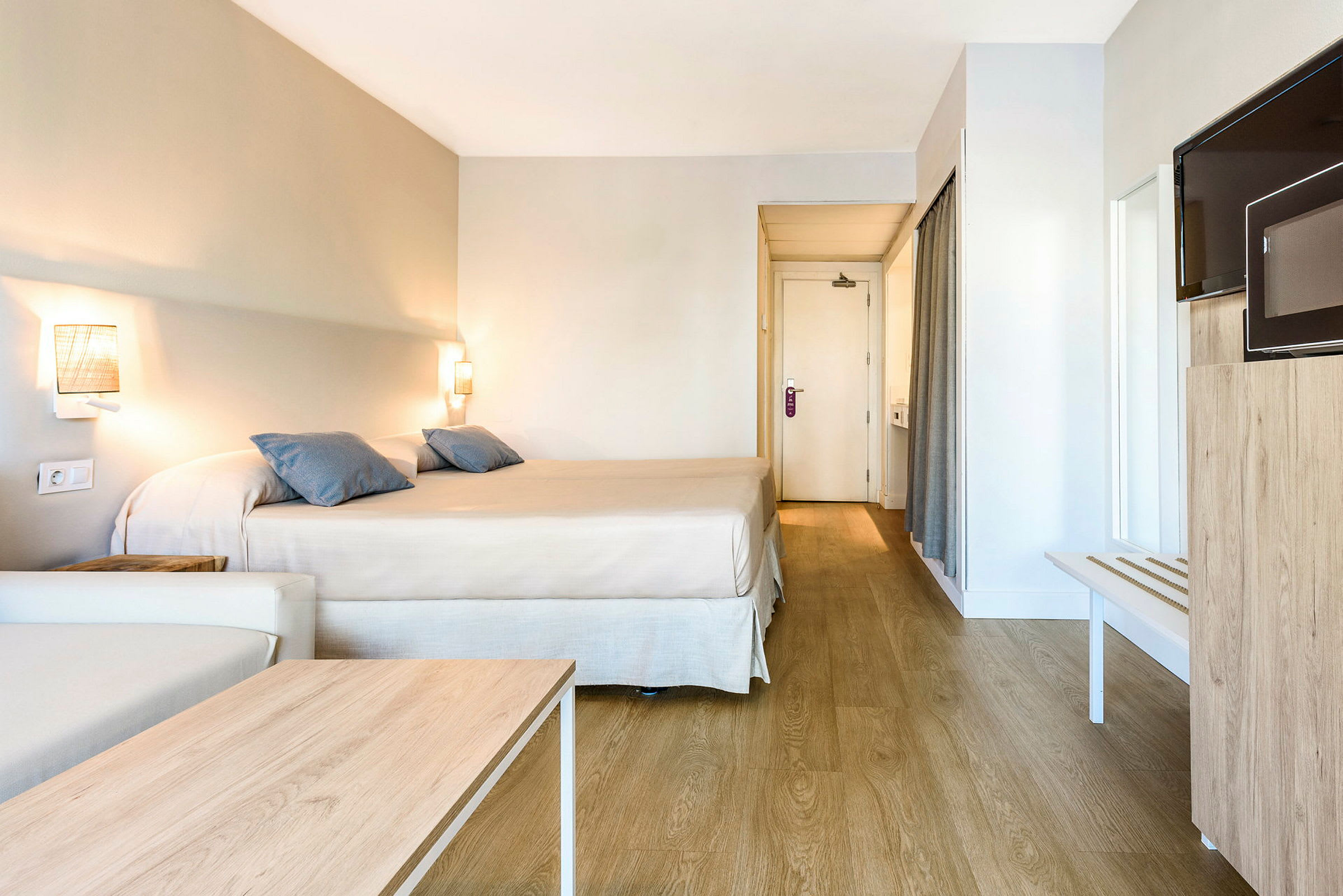 Hotelrum med en dubbelsäng, en soffa, ett träbord, en TV och en dörr till badrummet. (AI-genererad text)