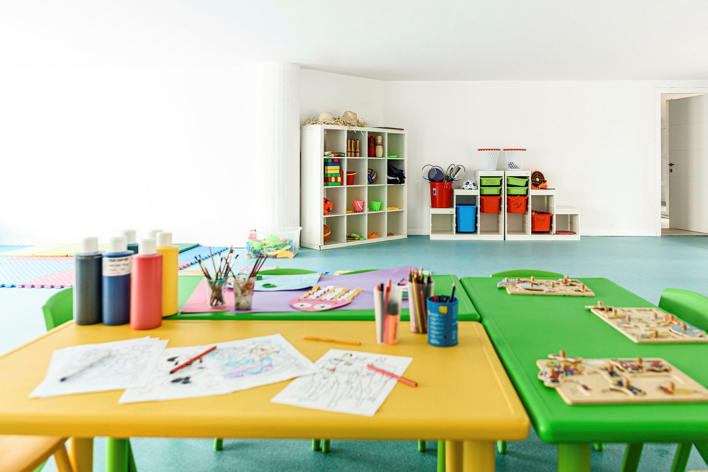 Ett barnpysselrum med bord, stolar och material för kreativt skapande. (AI-genererad text)