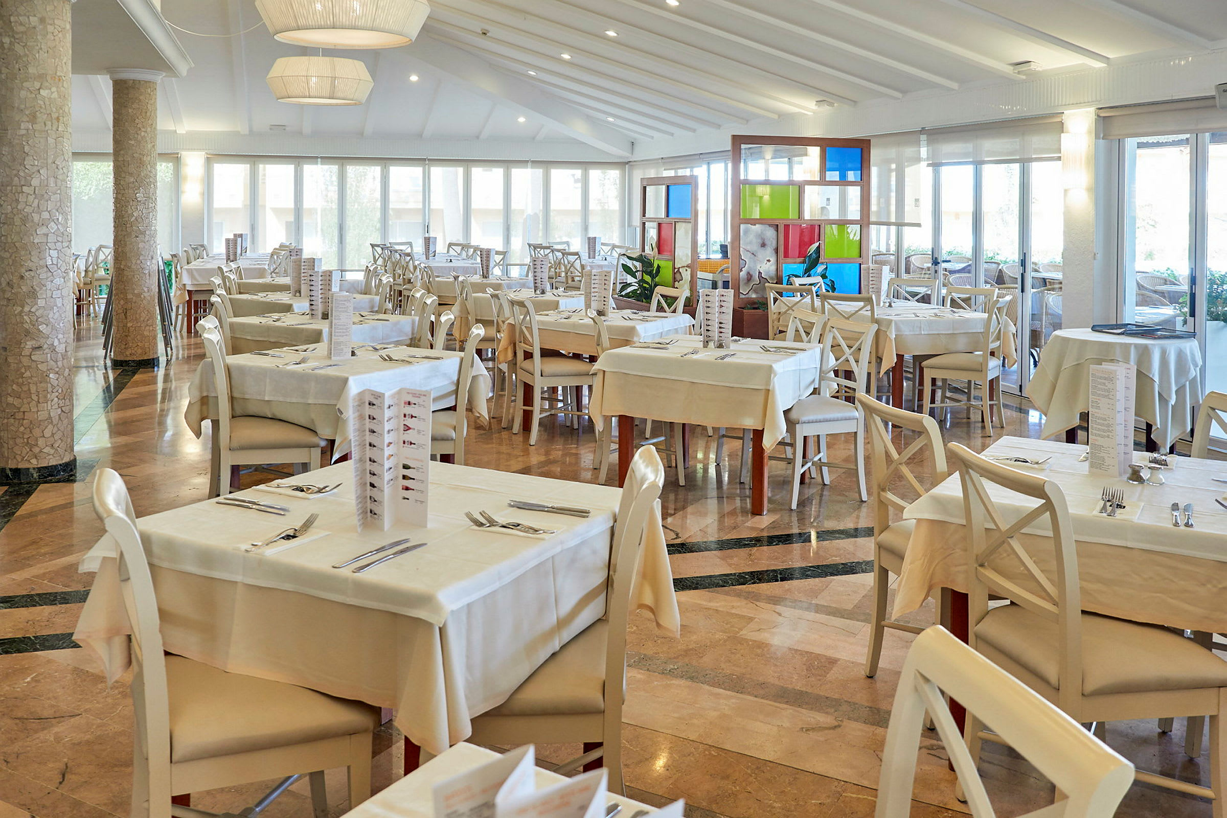 Ett ljus och rymlig restaurang med dukade bord och stolar. (AI-genererad text)