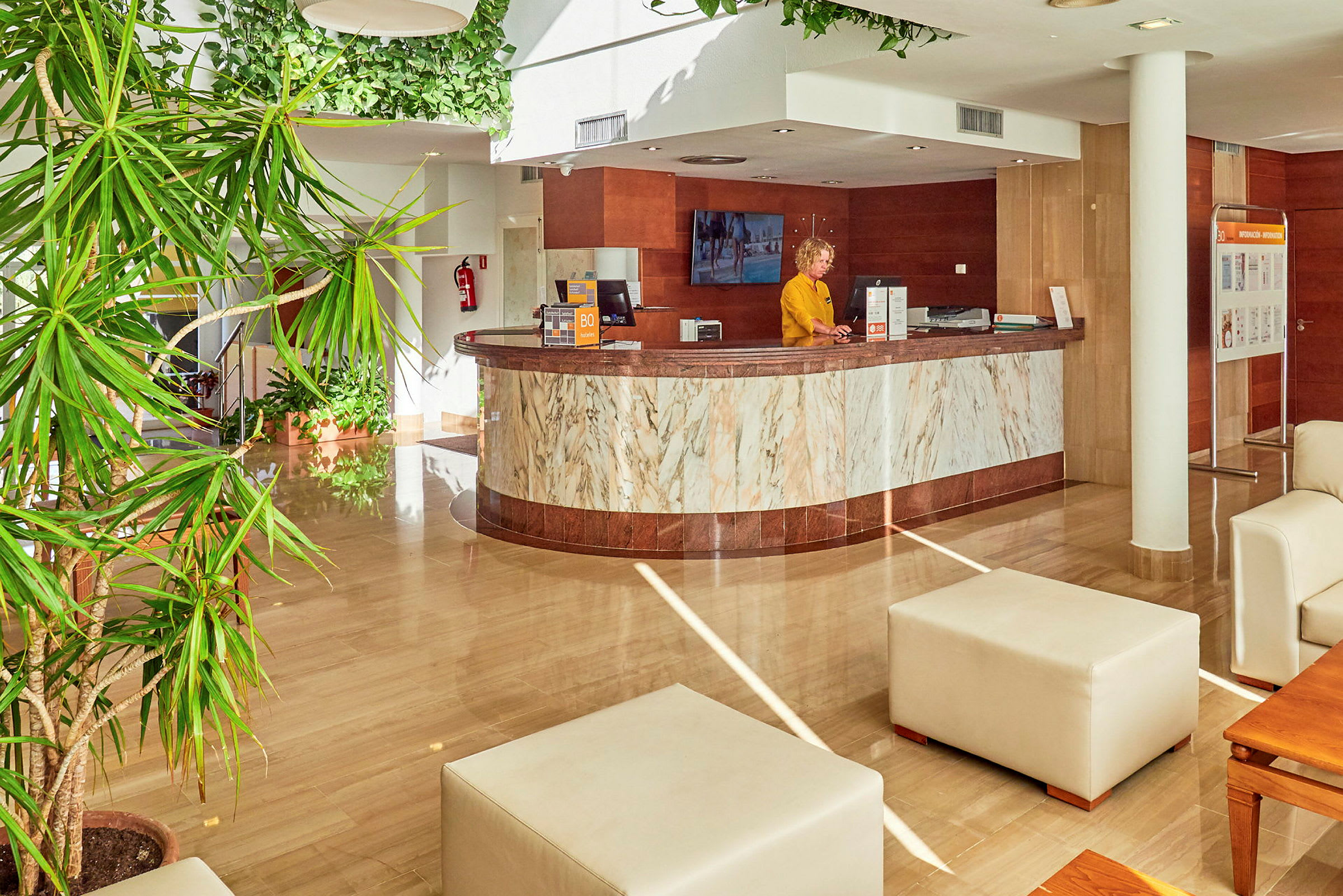 Hotellreception med marmorinredning och gröna växter. (AI-genererad text)