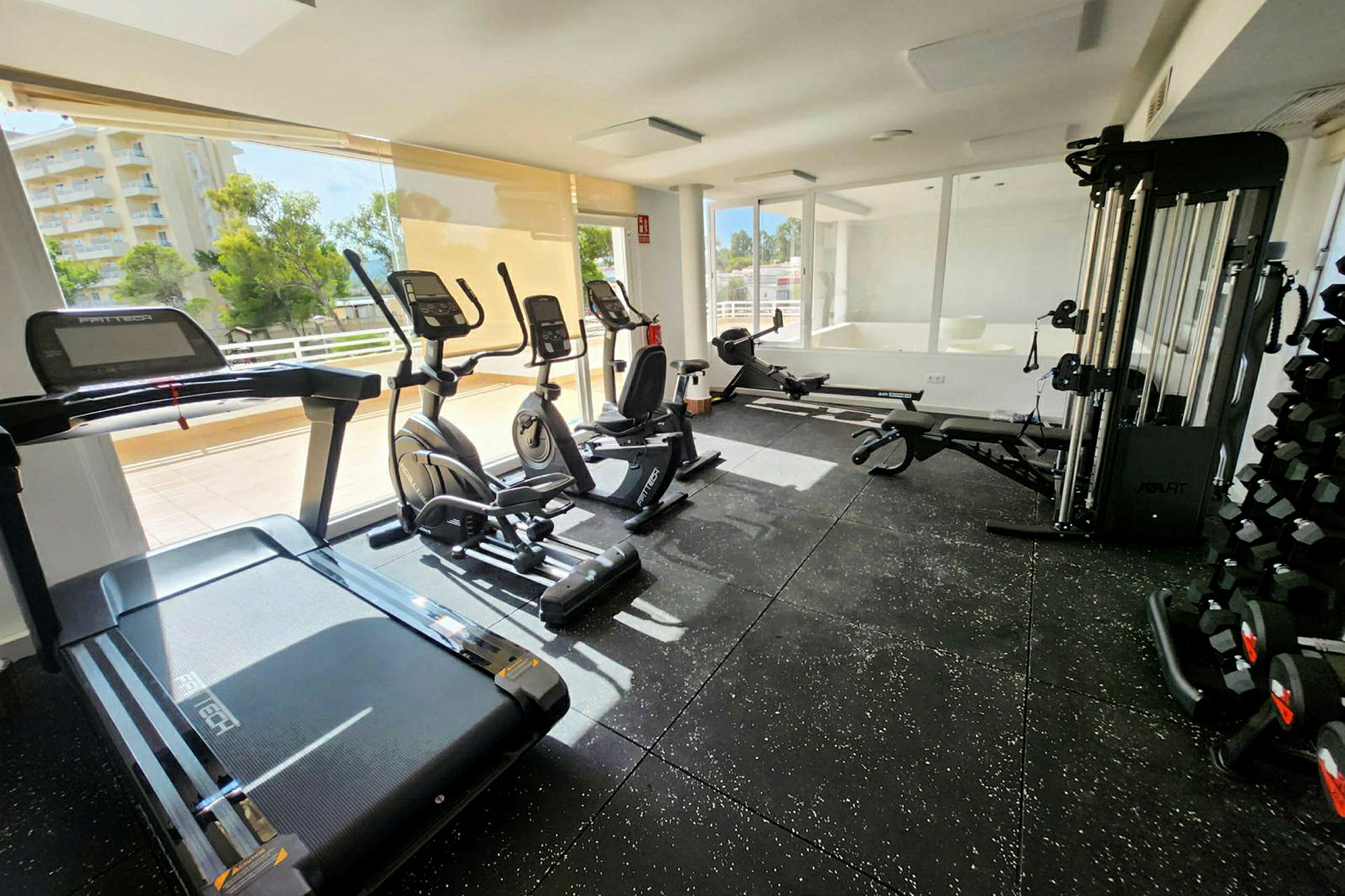Ett gym med träningsmaskiner inklusive löpband, elliptiska tränare och vikter. (AI-genererad text)