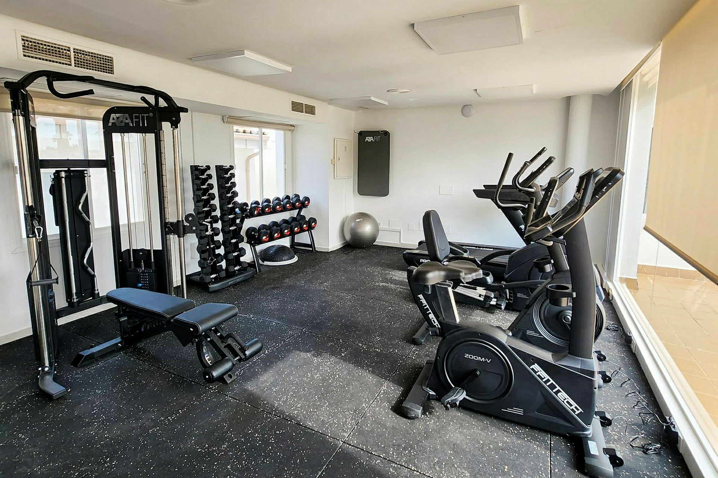 Ett gym med träningsutrustning, inklusive träningsmaskiner, hantlar och bänkar. (AI-genererad text)
