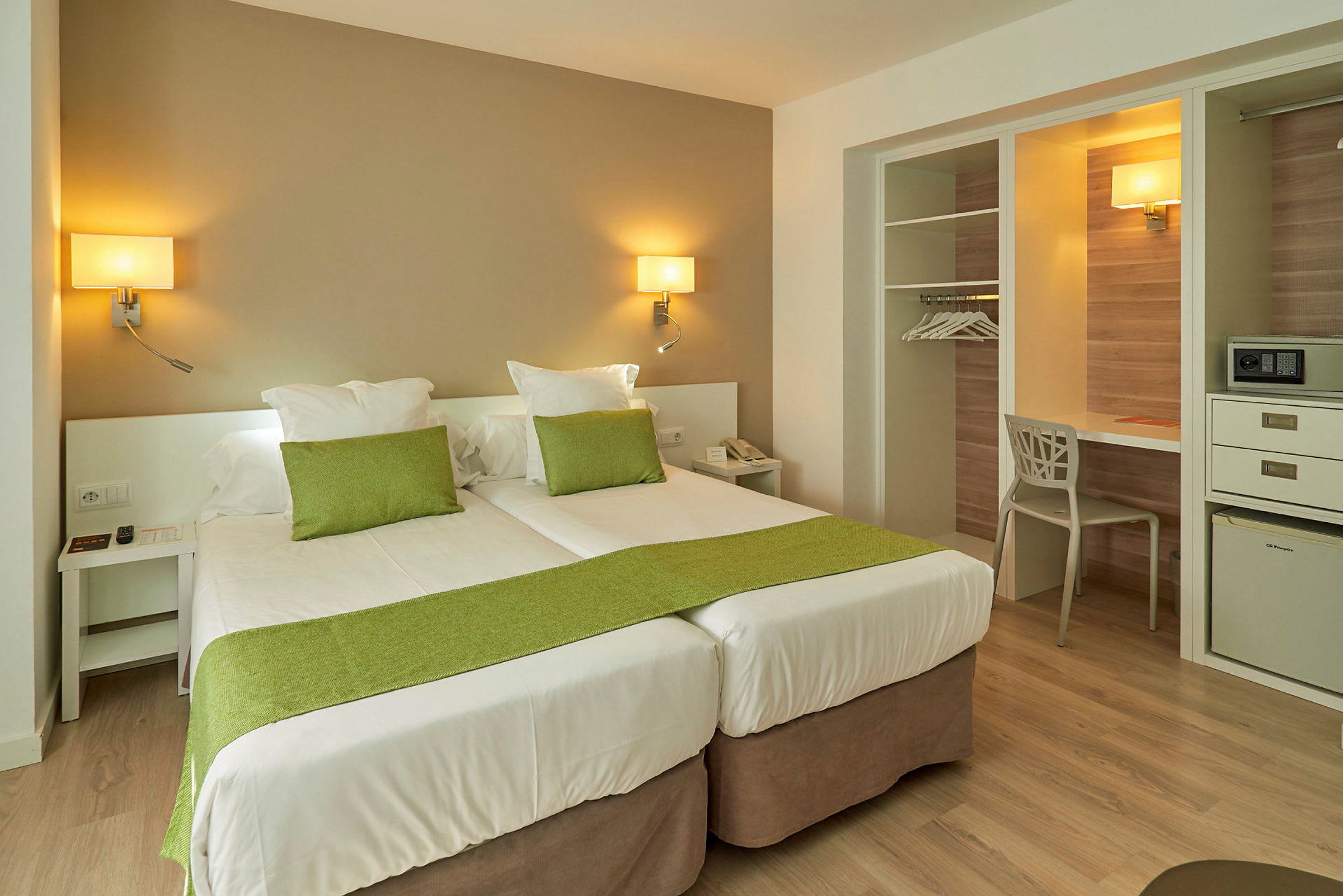 Hotelrum med två enkelsängar och grön dekoration. (AI-genererad text)