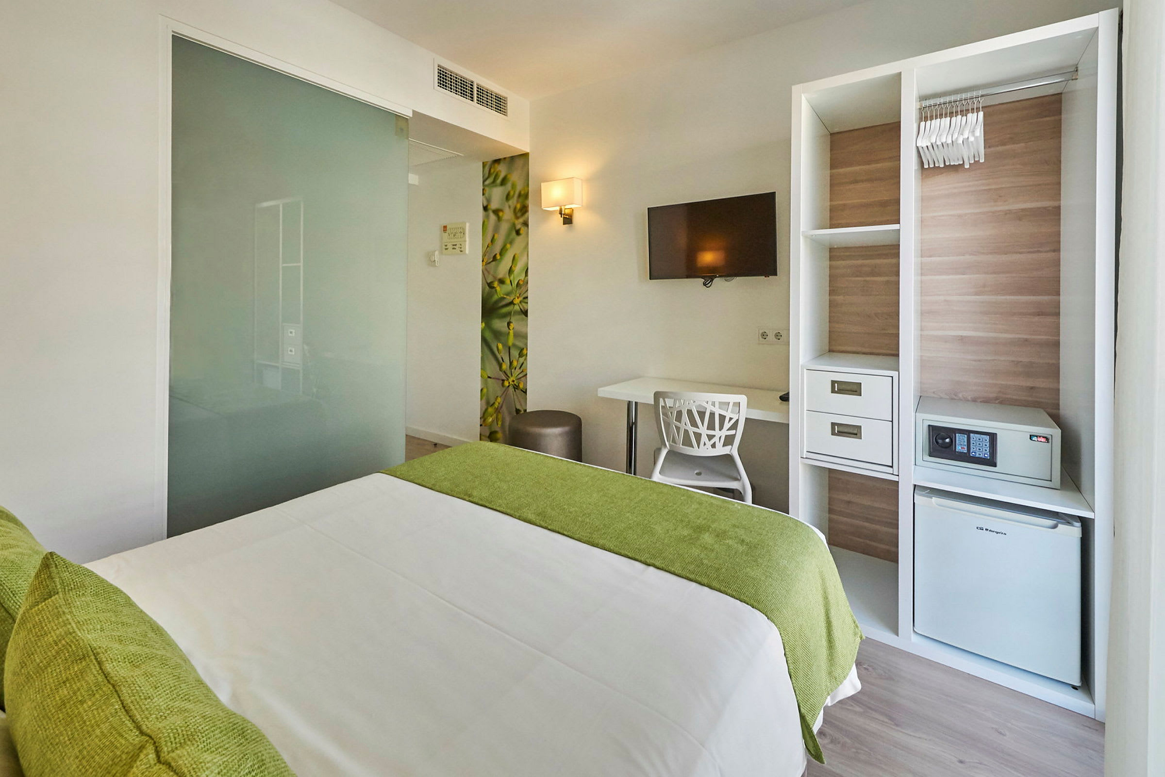 Modernt hotellrum med säng, skrivbord, tv och garderob. (AI-genererad text)
