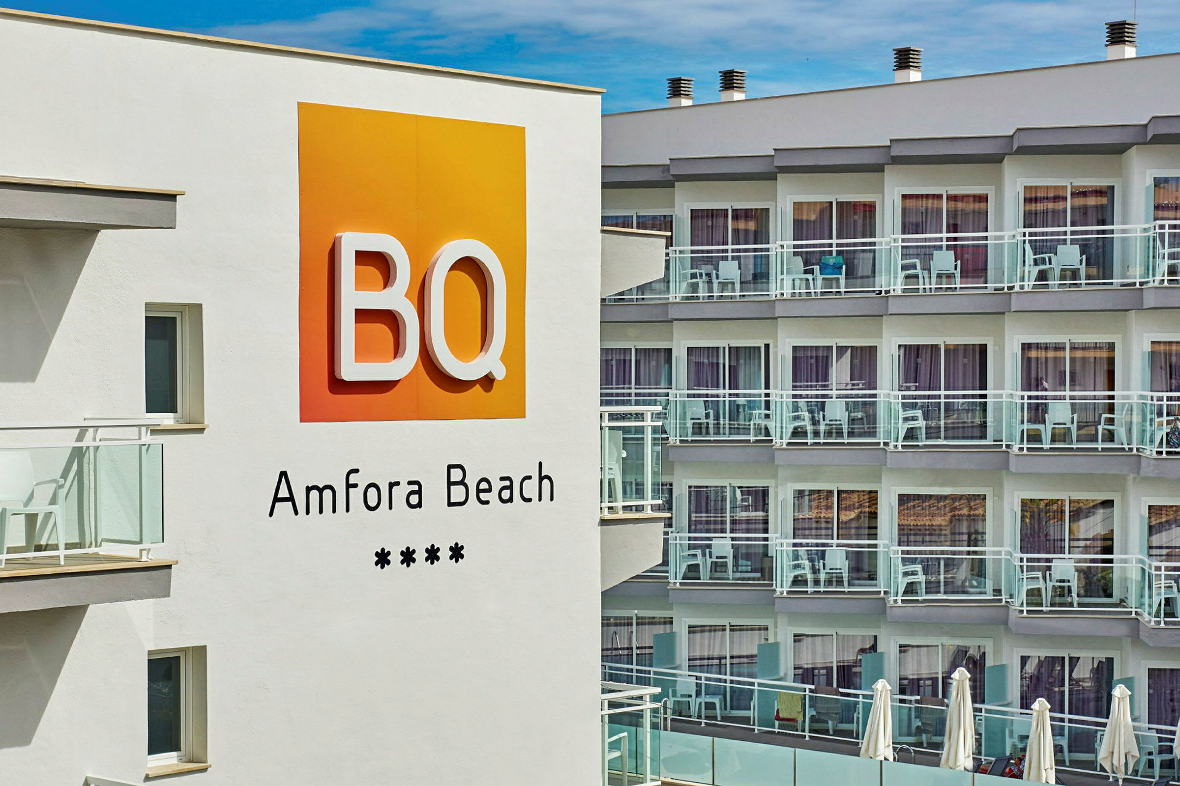 Hotellskylt med texten "BQ Amfora Beach" framför en byggnad med balkonger. (AI-genererad text)