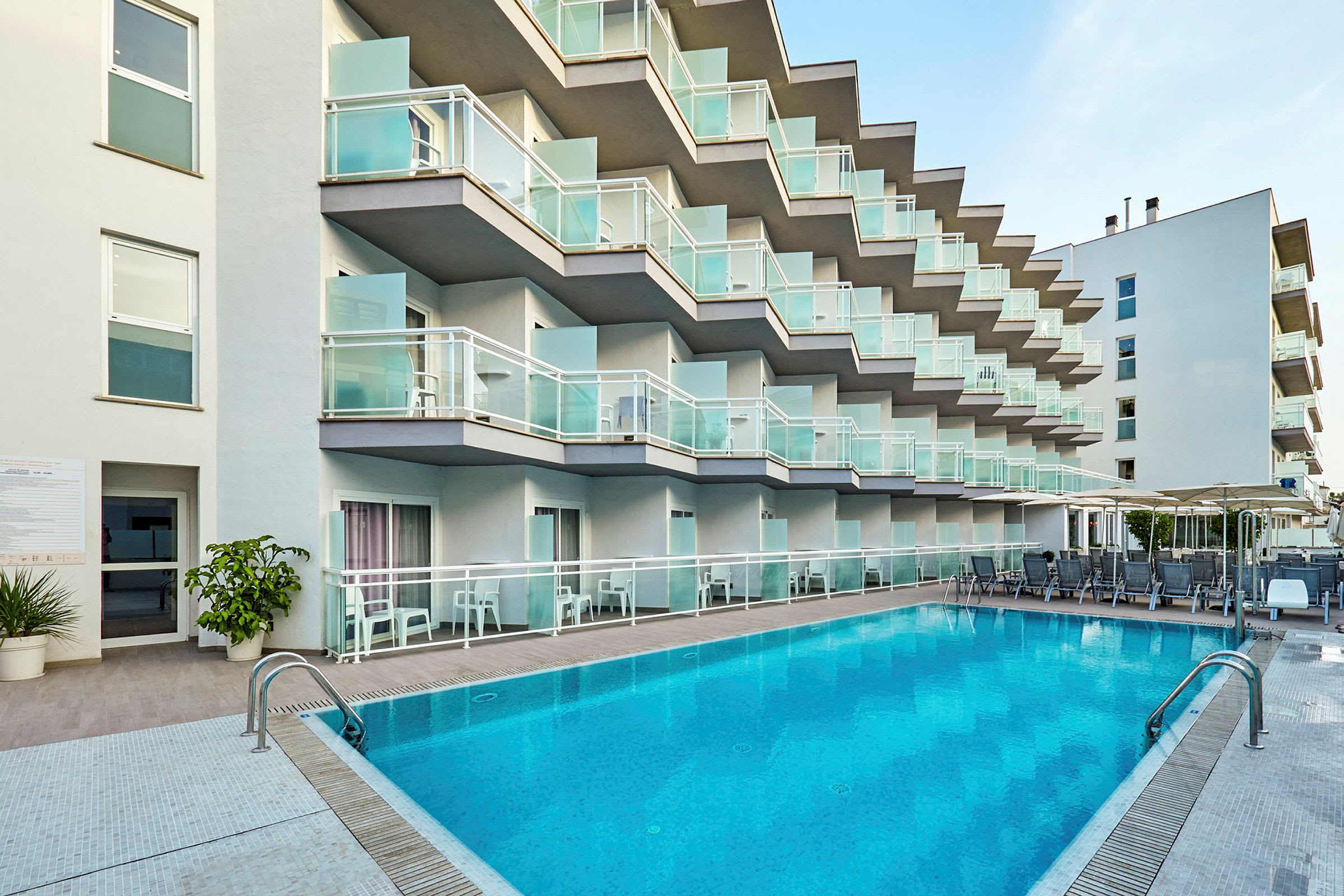 Hotellfasad med balkonger och pool i förgrunden. (AI-genererad text)