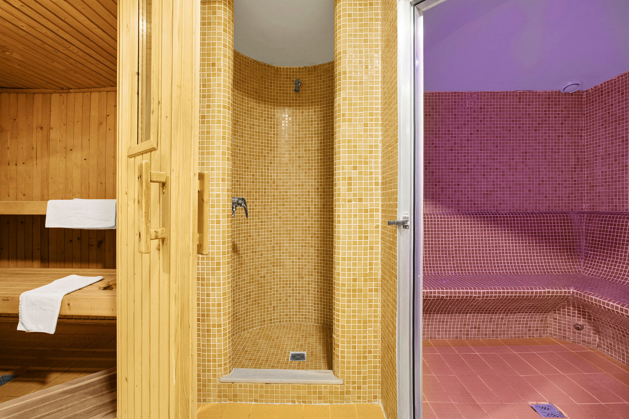 Tre områden: bastu i trä, dusch med mosaik i beige och ångbastu med mosaik i rött. (AI-genererad text)