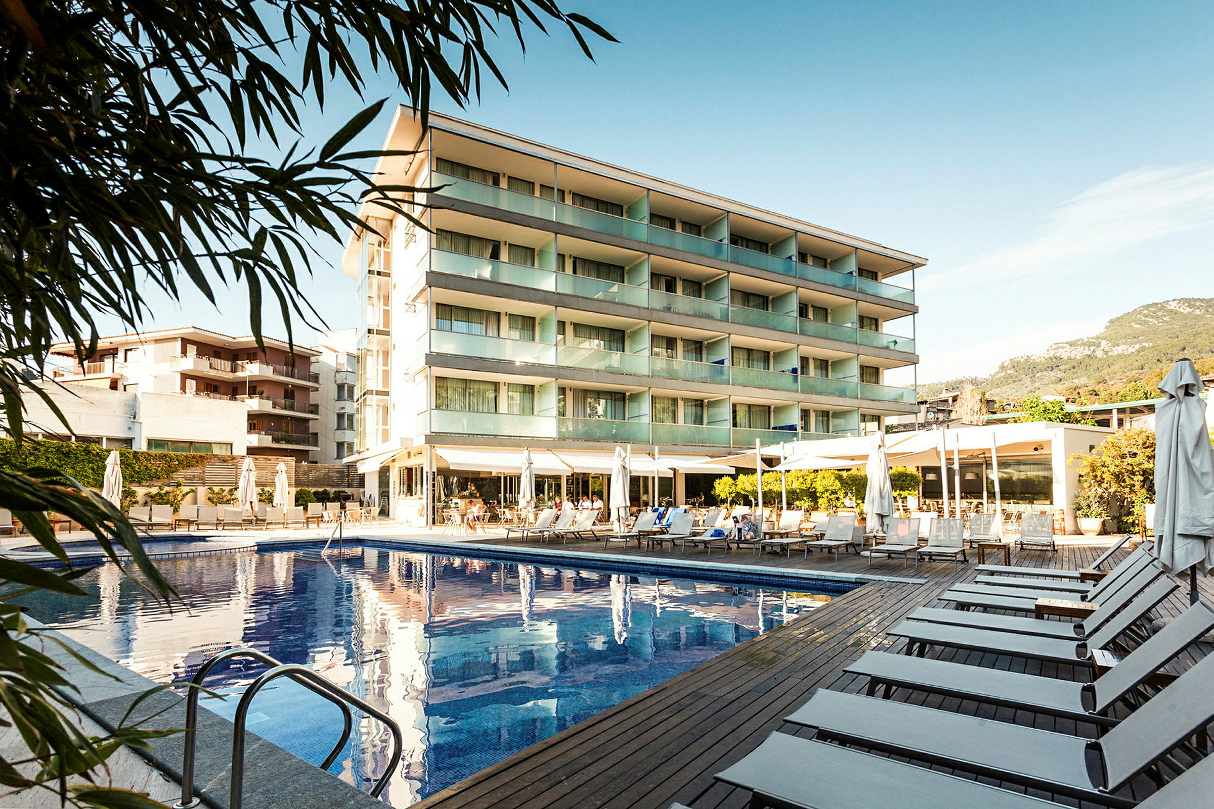 Bild av ett hotell med swimmingpool och solstolar utomhus. (AI-genererad text)