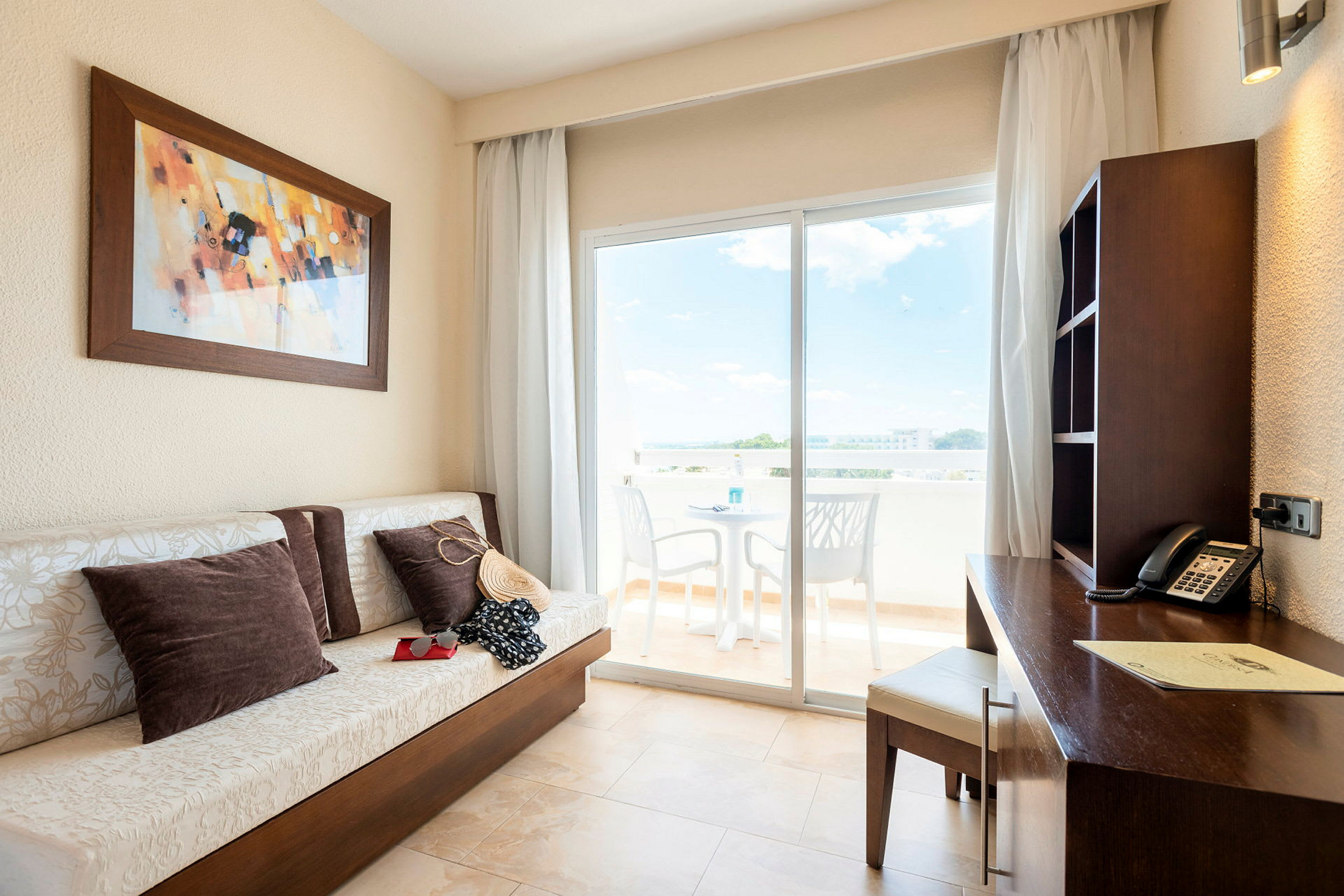 Hotellrum med soffa, skrivbord och balkong med utsikt. (AI-genererad text)