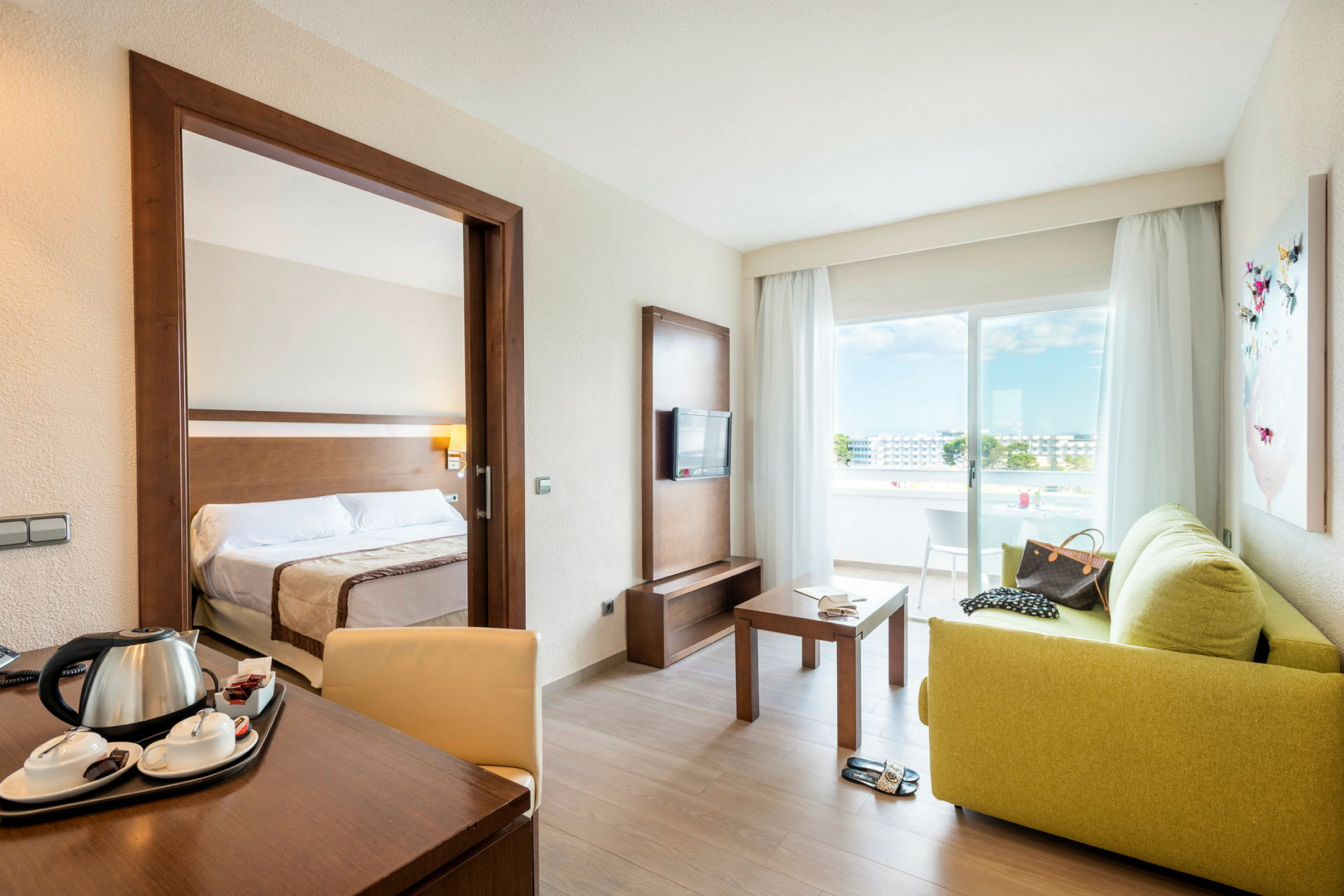 Hotellrum med separerat sovrum, sittgrupp, balkong och utsikt. (AI-genererad text)