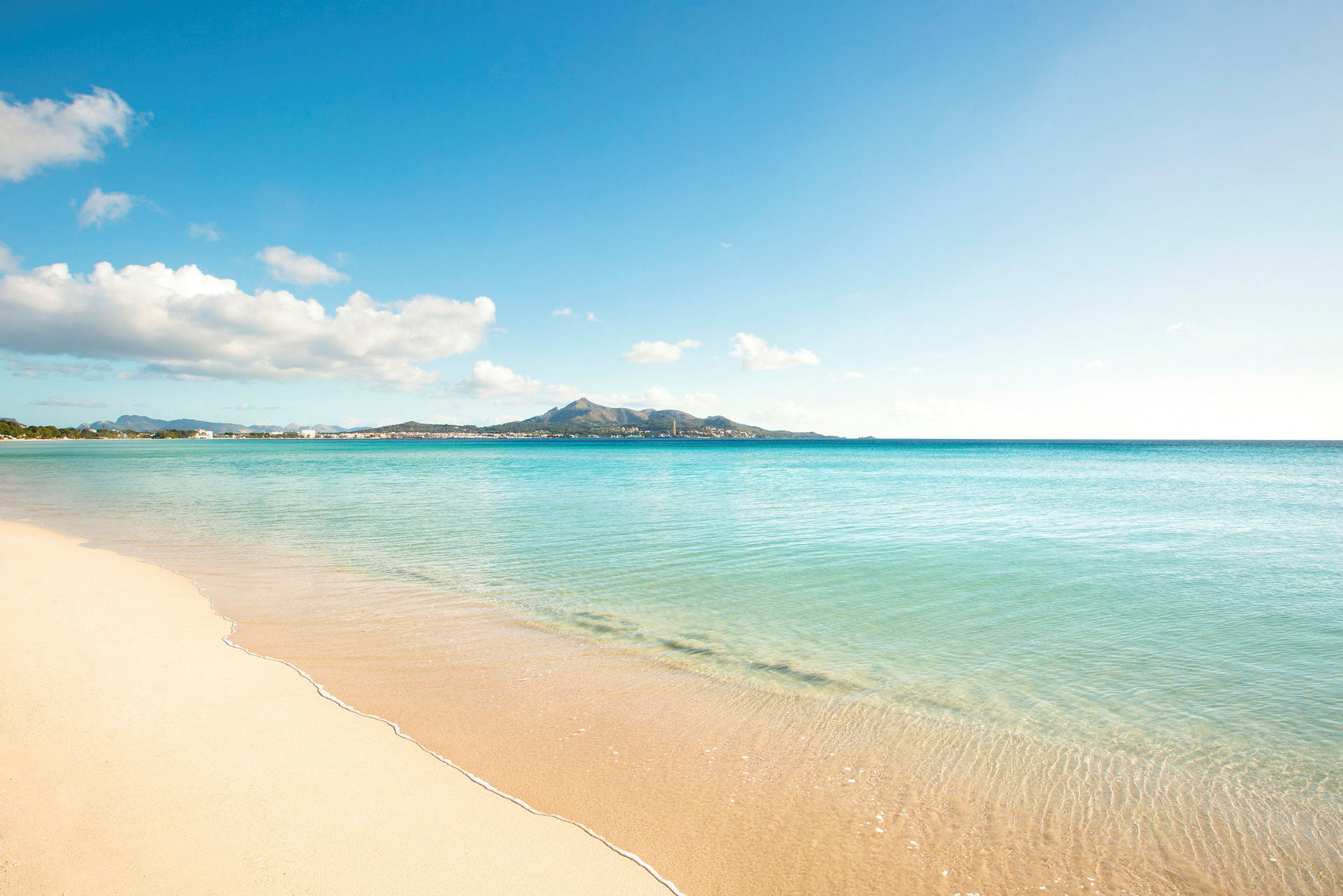 Bild av en sandstrand med turkost vatten under en blå himmel. (AI-genererad text)
