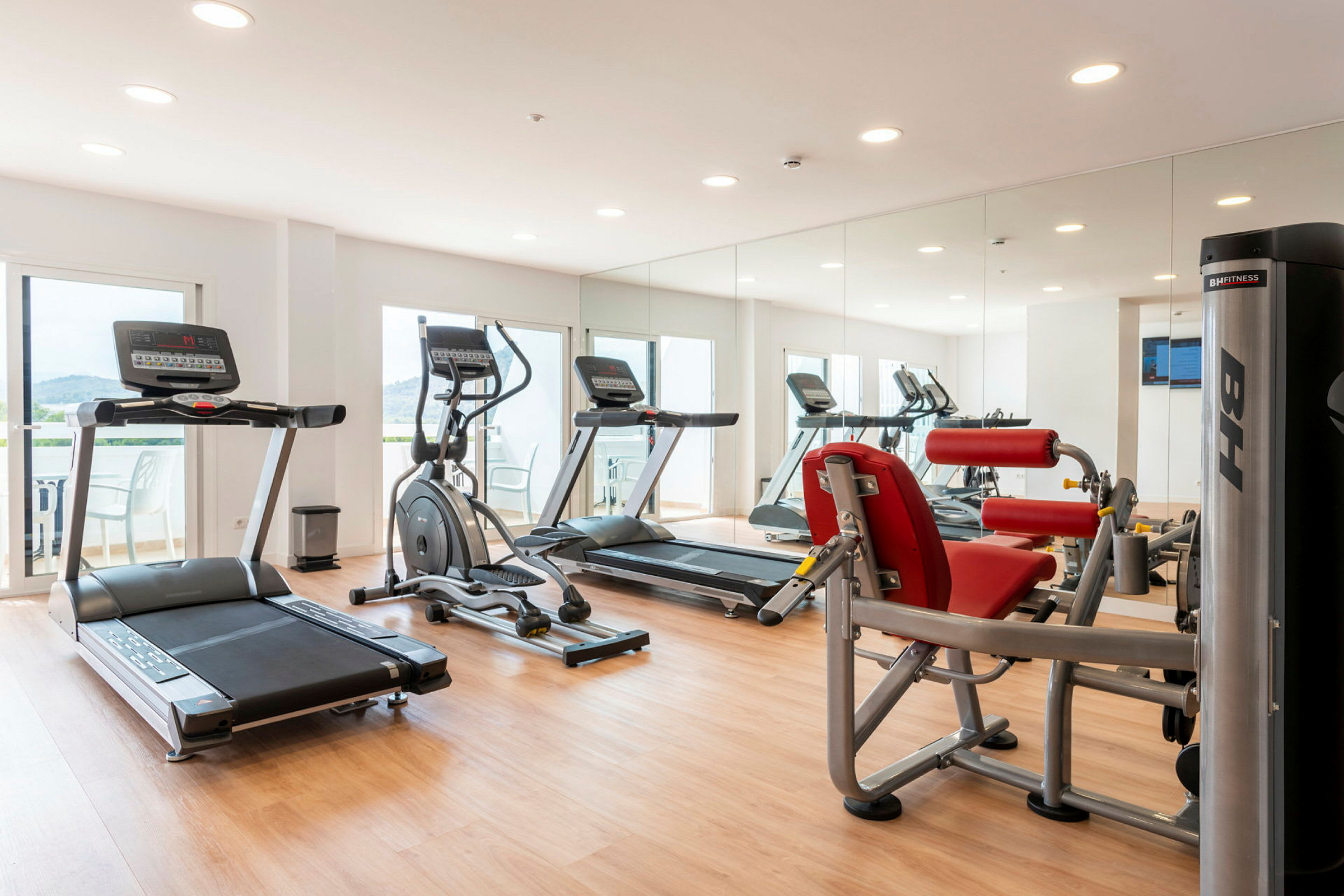 Gym med träningsmaskiner, spegelvägg och parkettgolv. (AI-genererad text)