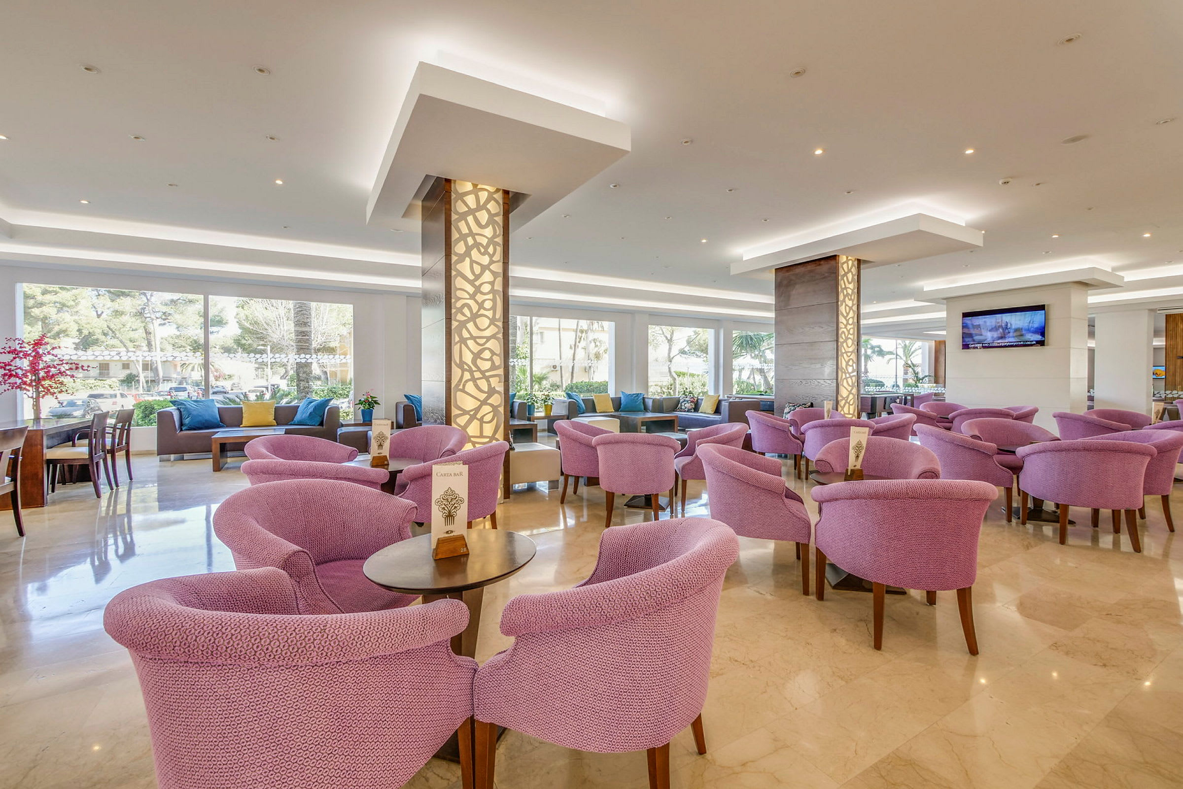 Interiör av en ljus lounge med lila fåtöljer och bord. (AI-genererad text)