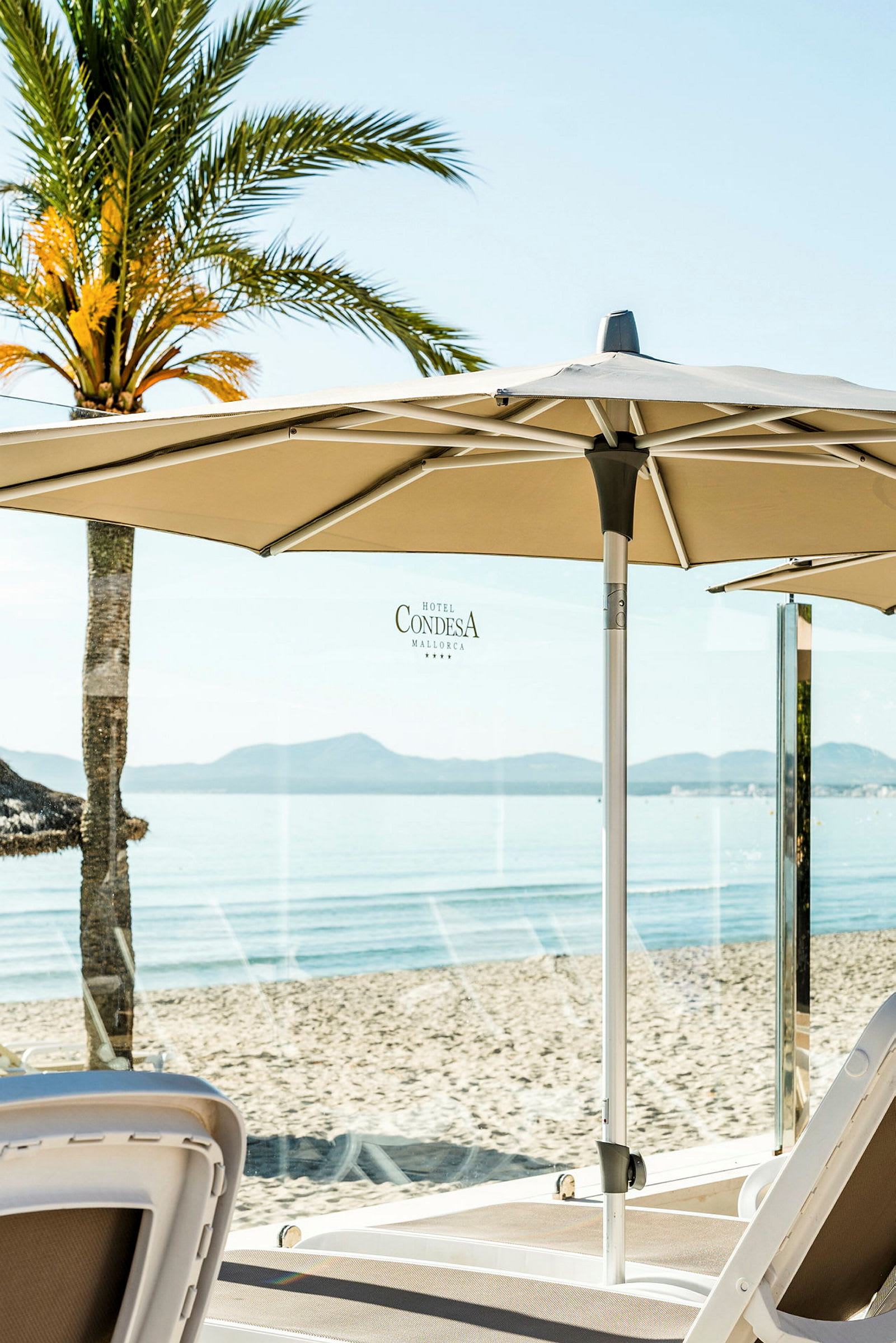 Strand med solstolar och parasoll, palmträd i bakgrunden. (AI-genererad text)