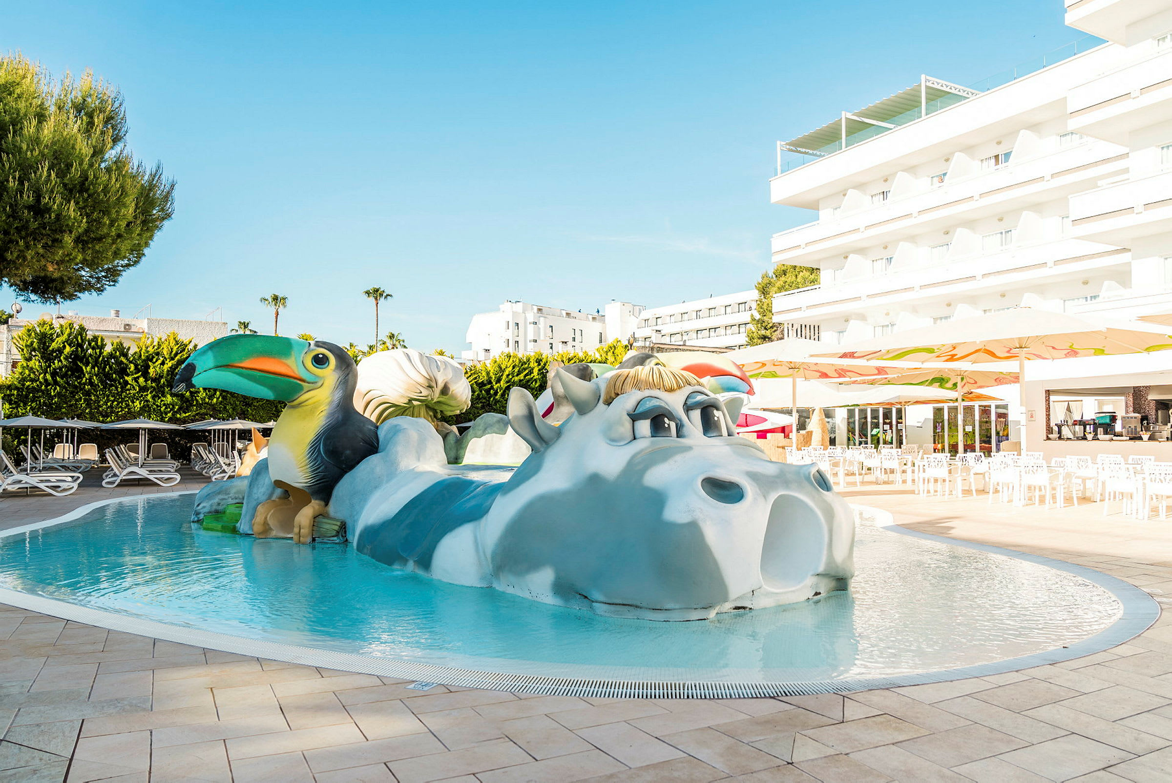 Pool med dekorativt djurmotiv, omgiven av solstolar och byggnader. (AI-genererad text)