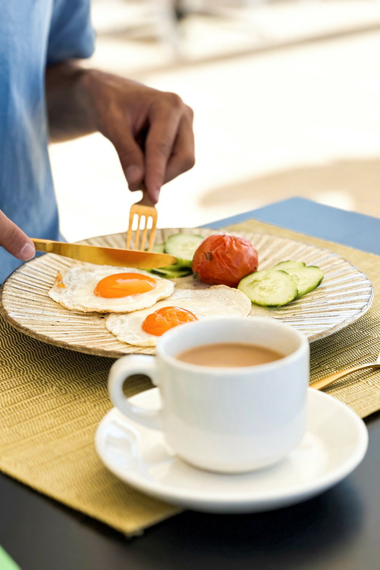 En person äter frukost som består av stekta ägg, tomat, gurkskivor och kaffe. (AI-genererad text)