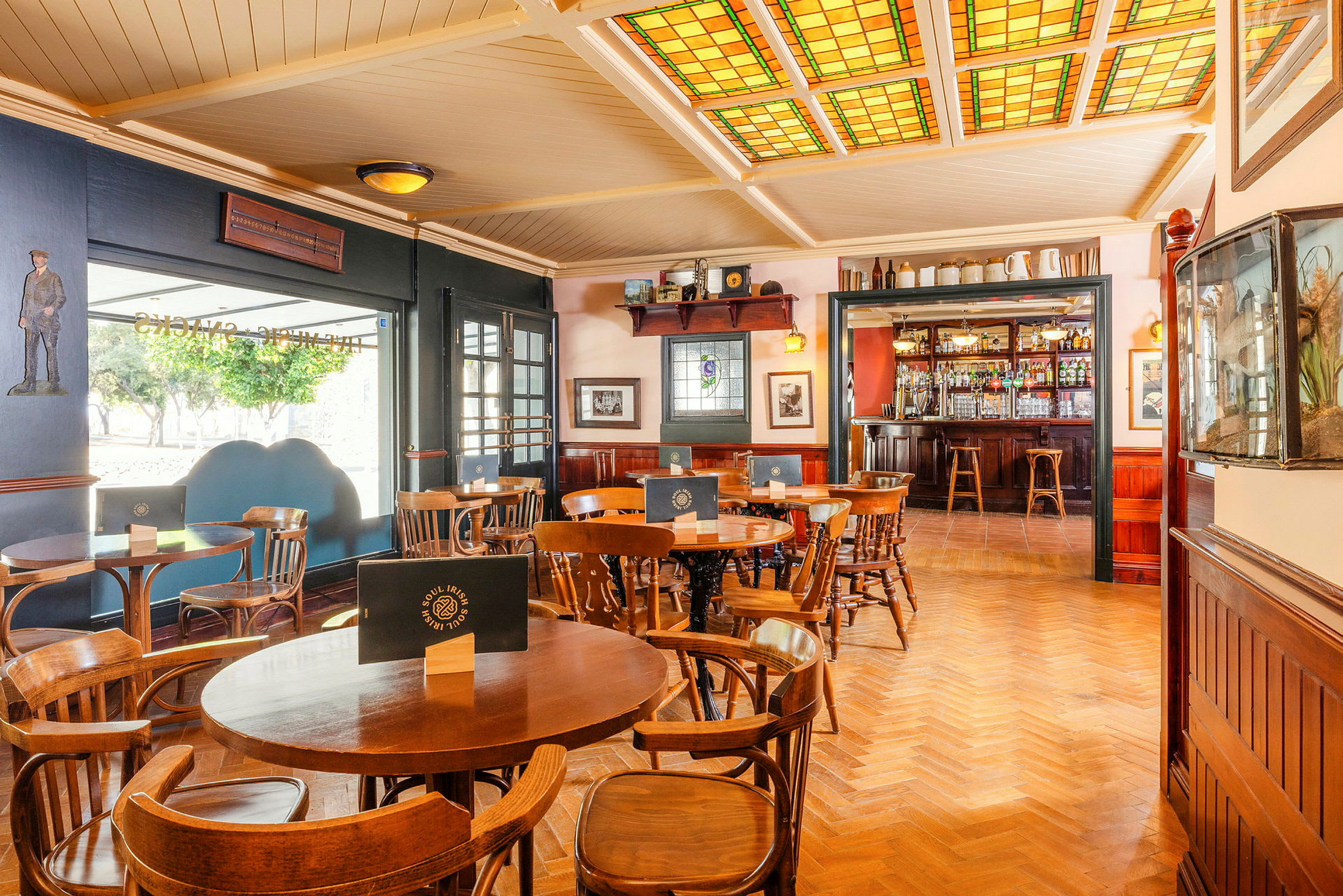Interiör av en pub med trästolar och bord samt en bar i bakgrunden. (AI-genererad text)