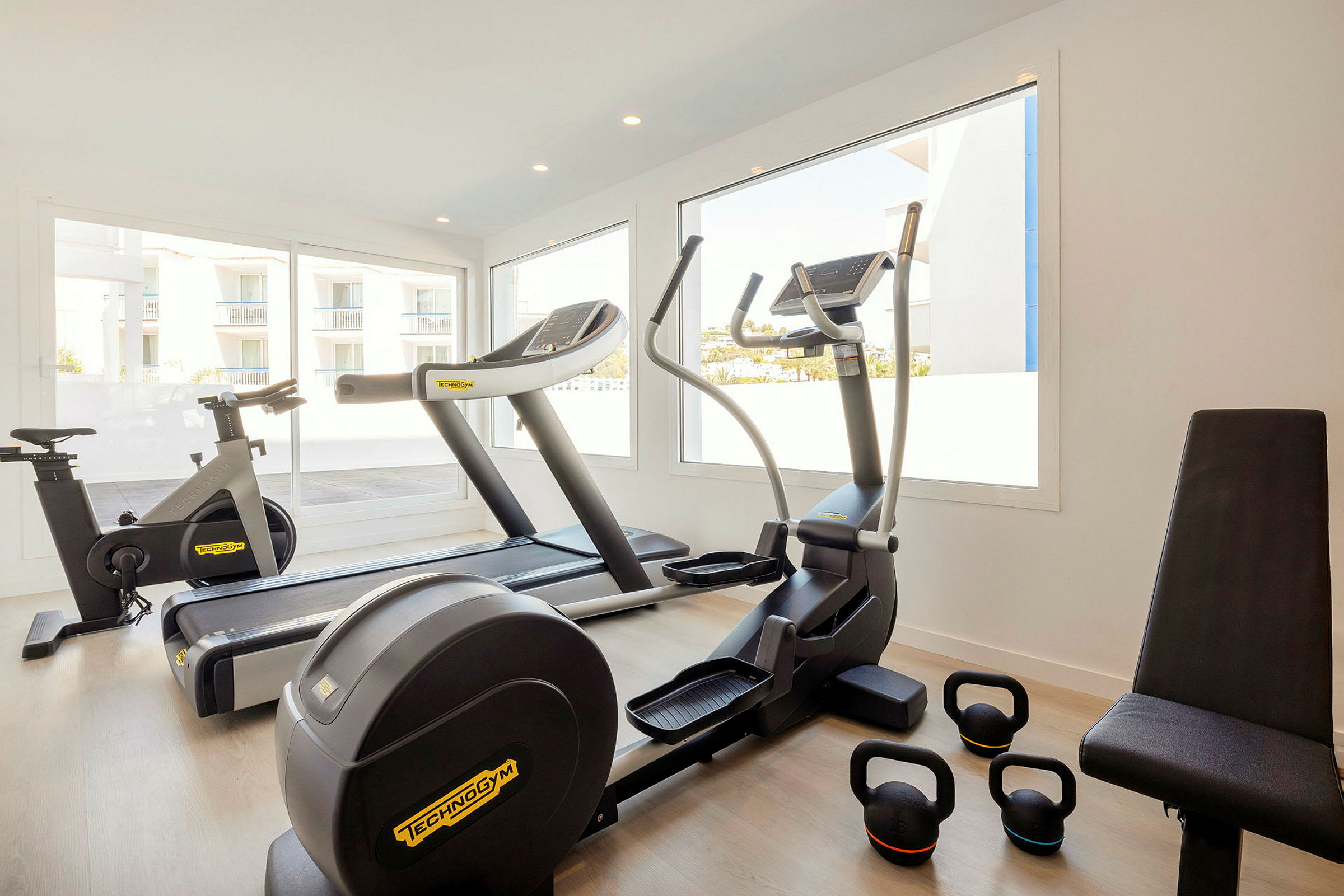 Ett gym med träningsutrustning såsom cykel, löpband, crosstrainer och kettlebells. (AI-genererad text)