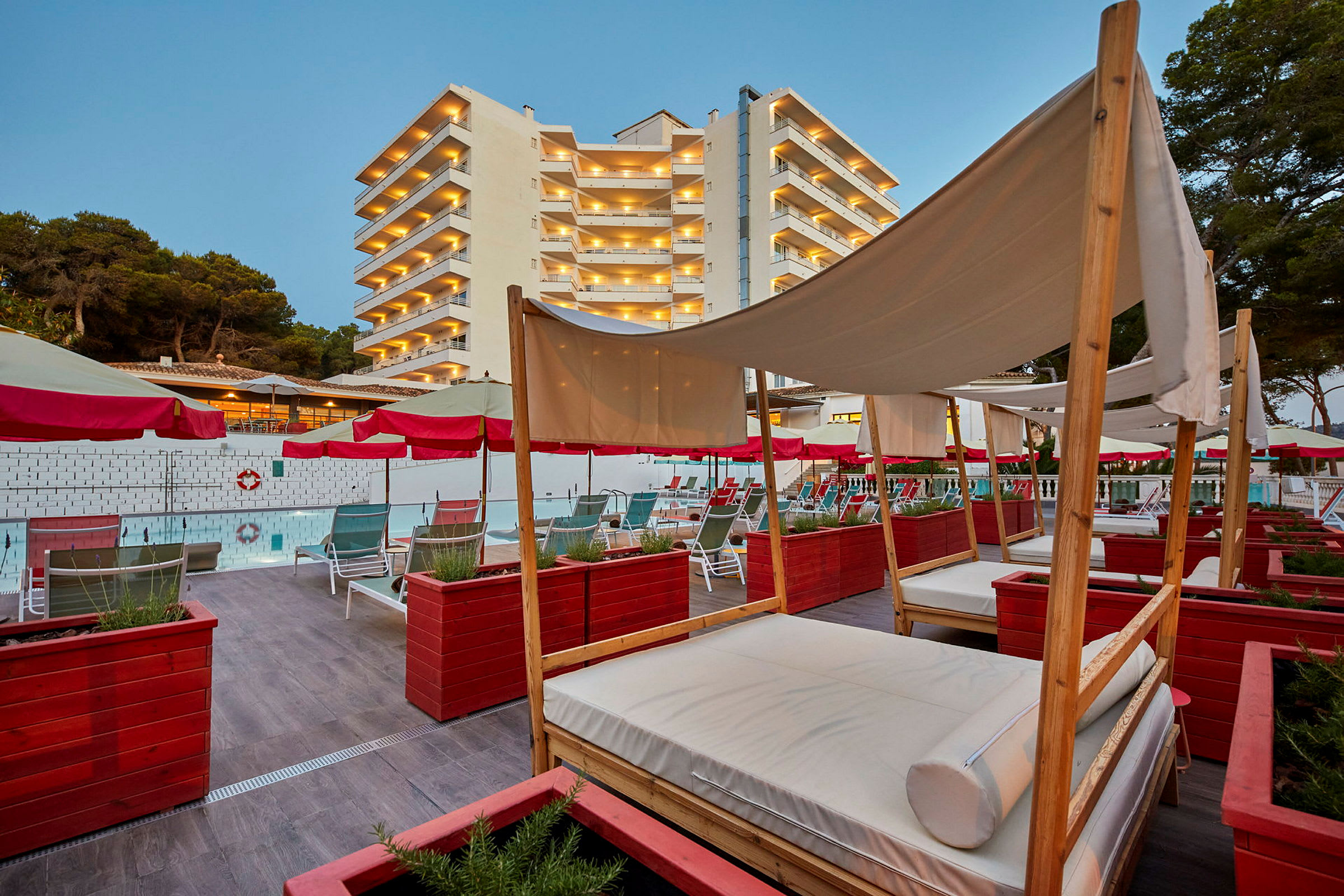 Poolområde med solstolar och baldakiner framför ett hotell med flera våningar. (AI-genererad text)