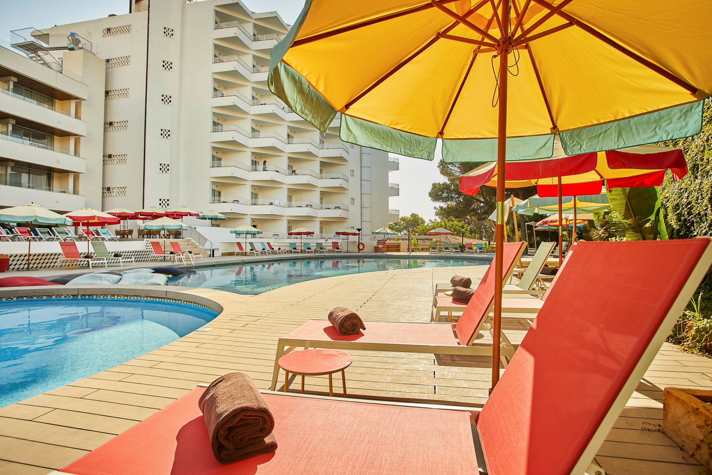 Solstolar och parasoller vid en swimmingpool bredvid ett hotell. (AI-genererad text)