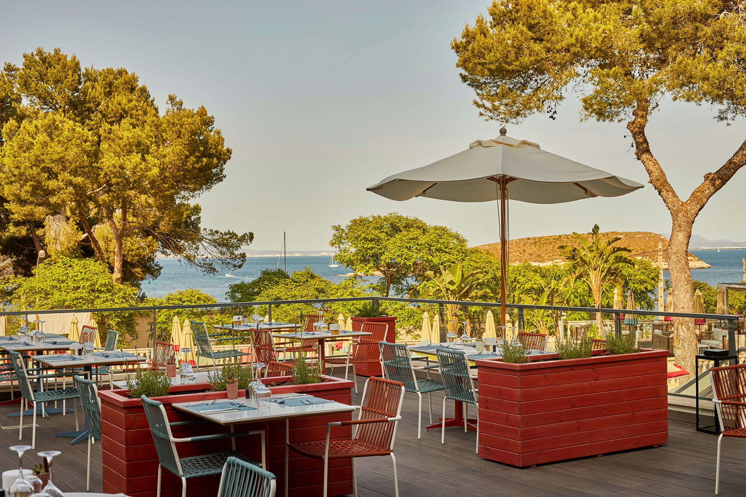 En terrass restaurang med utsikt över havet och tallskog. (AI-genererad text)