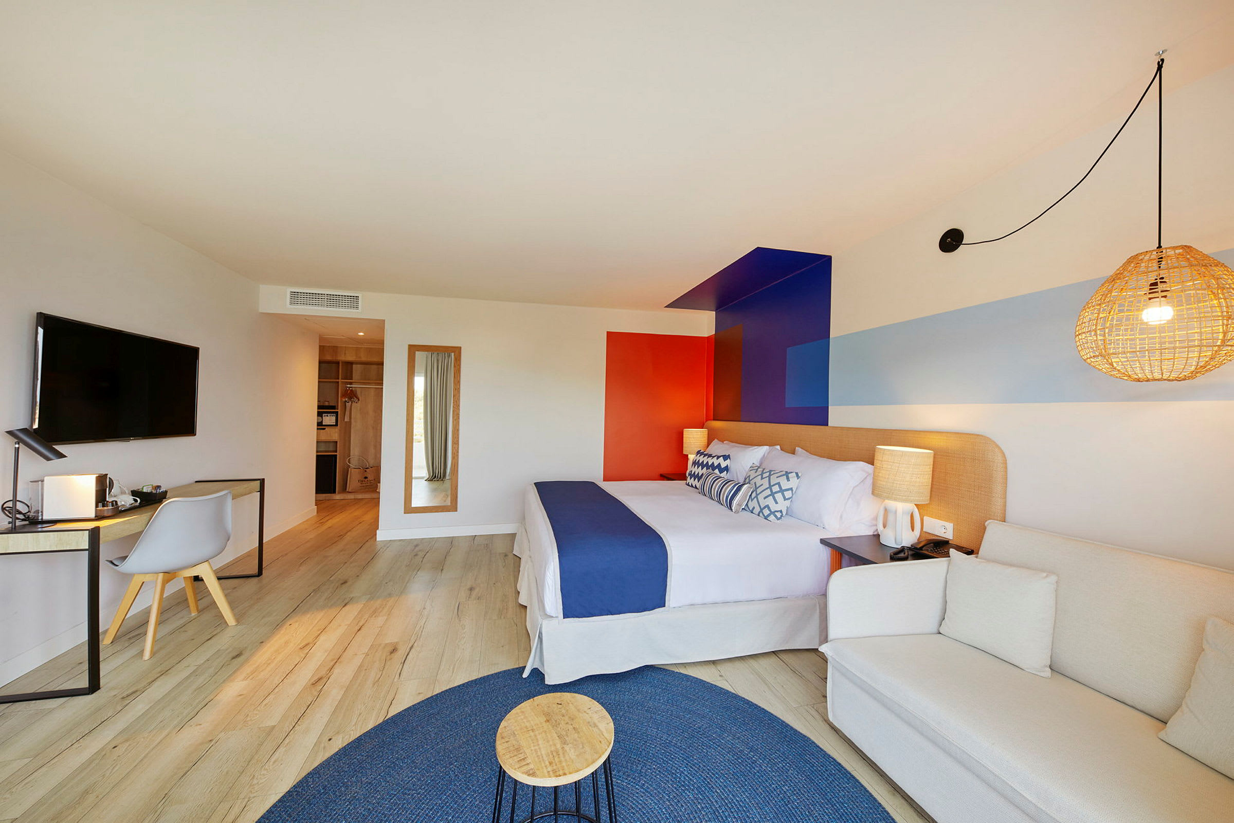 Ett modernt hotellrum med en bekväm säng, en skrivbordshörna och en sittgrupp, inrett med färgglada detaljer. (AI-genererad text)