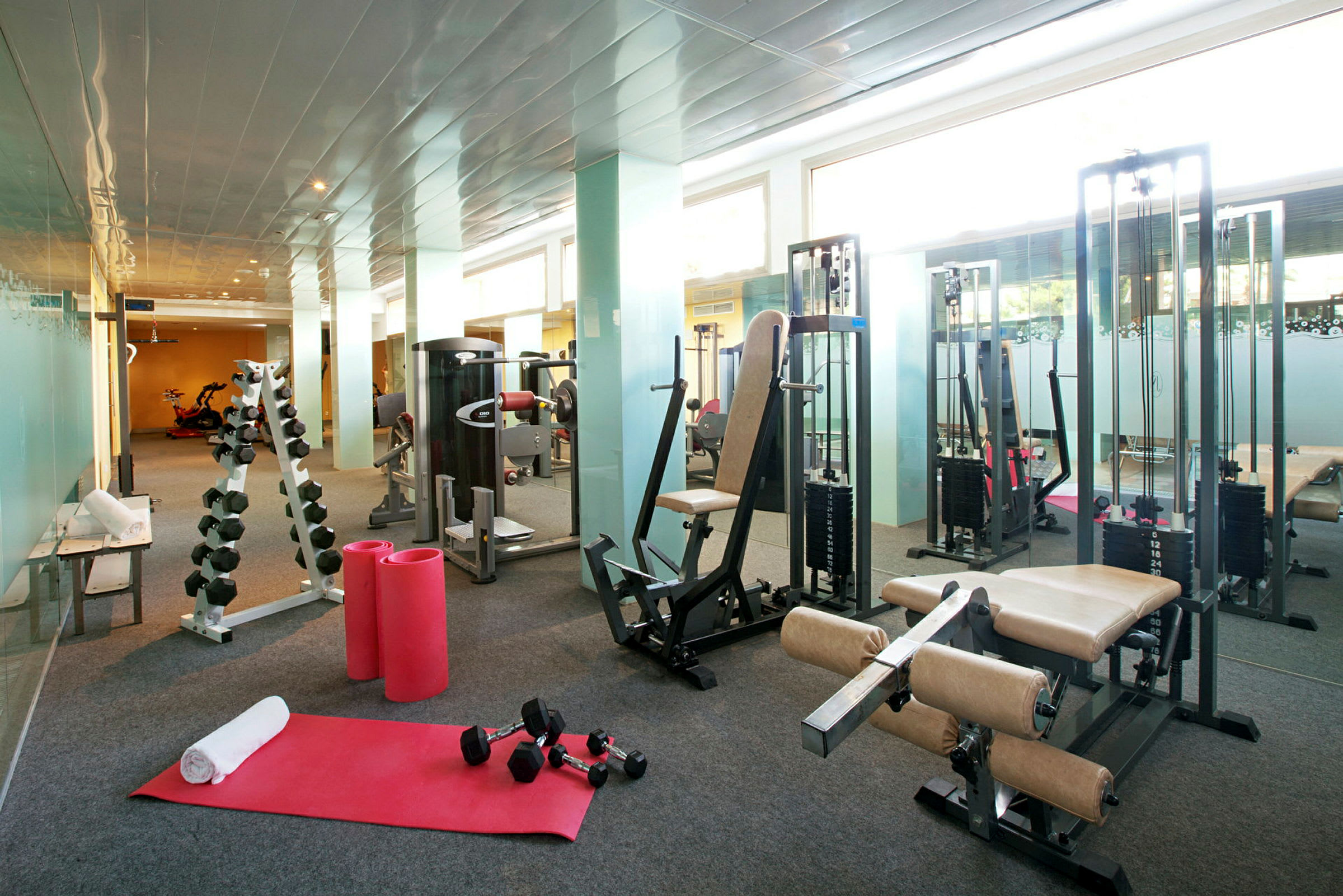 Gym med träningsutrustning, inklusive maskiner, vikter och träningsmattor. (AI-genererad text)