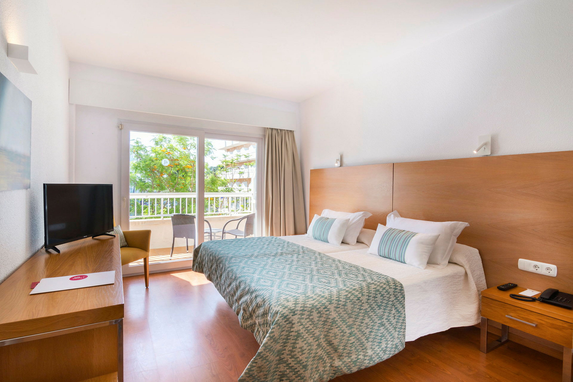 Hotellrum med dubbelsäng, träinredning, TV och sittmöbler samt balkong med utsikt. (AI-genererad text)