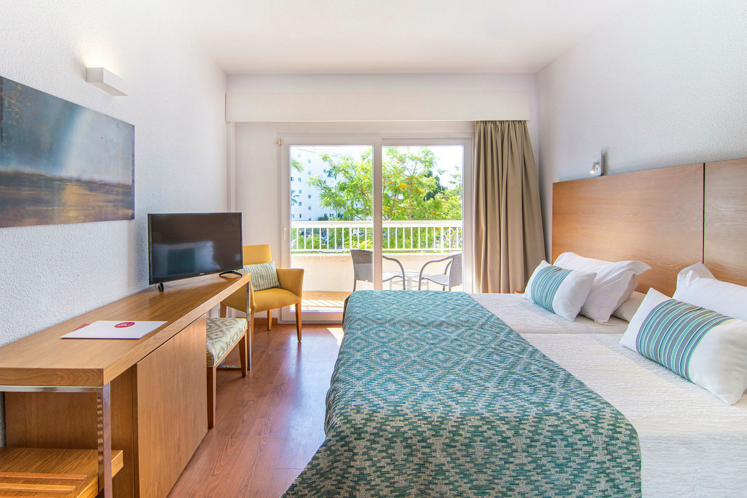 Hotellrum med två bäddar, skrivbord, och fönster med utsikt mot balkong. (AI-genererad text)