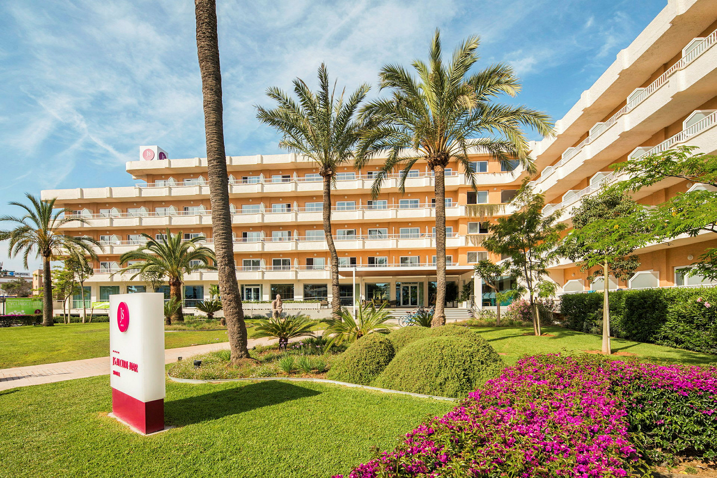 Ett flervåningshotell omgivet av välskött grönska och palmer. (AI-genererad text)