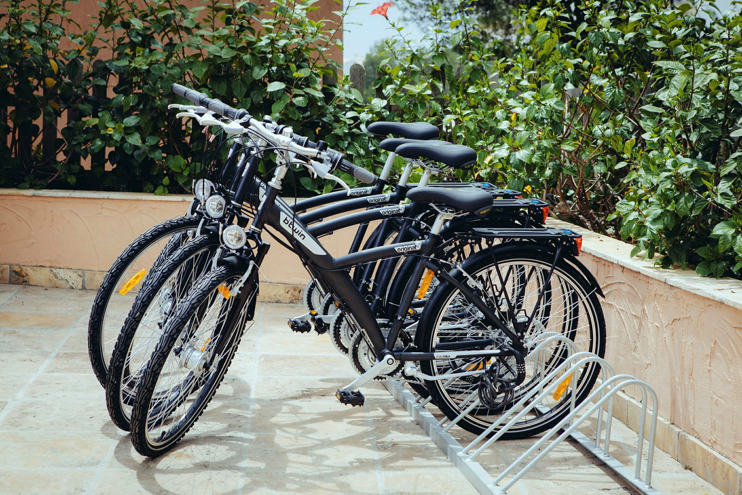 Flera cyklar parkerade i ett cykelställ vid en växtbeklädd vägg. (AI-genererad text)
