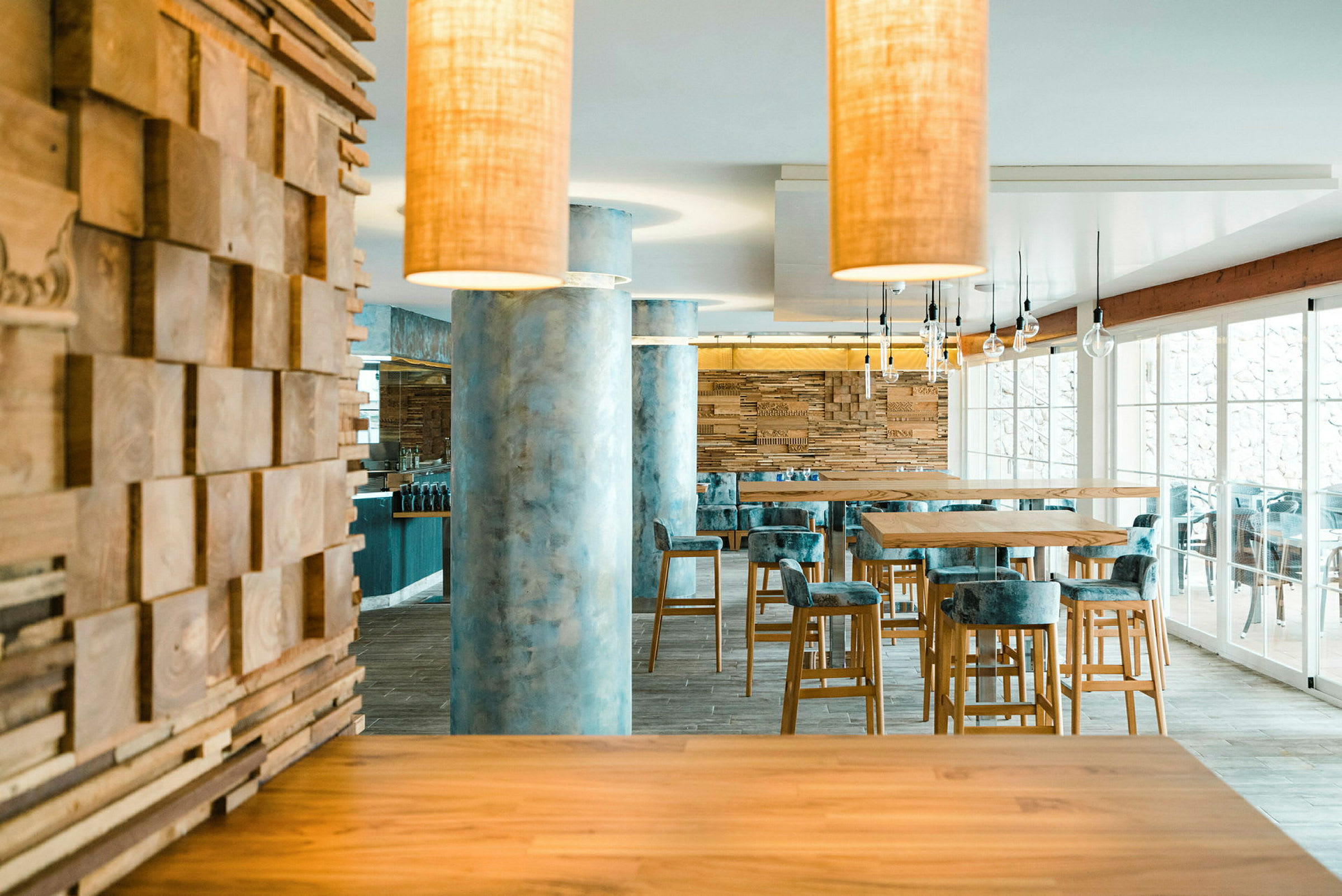 Modern restauranginteriör med trä och marmor samt höga bord och stolar. (AI-genererad text)