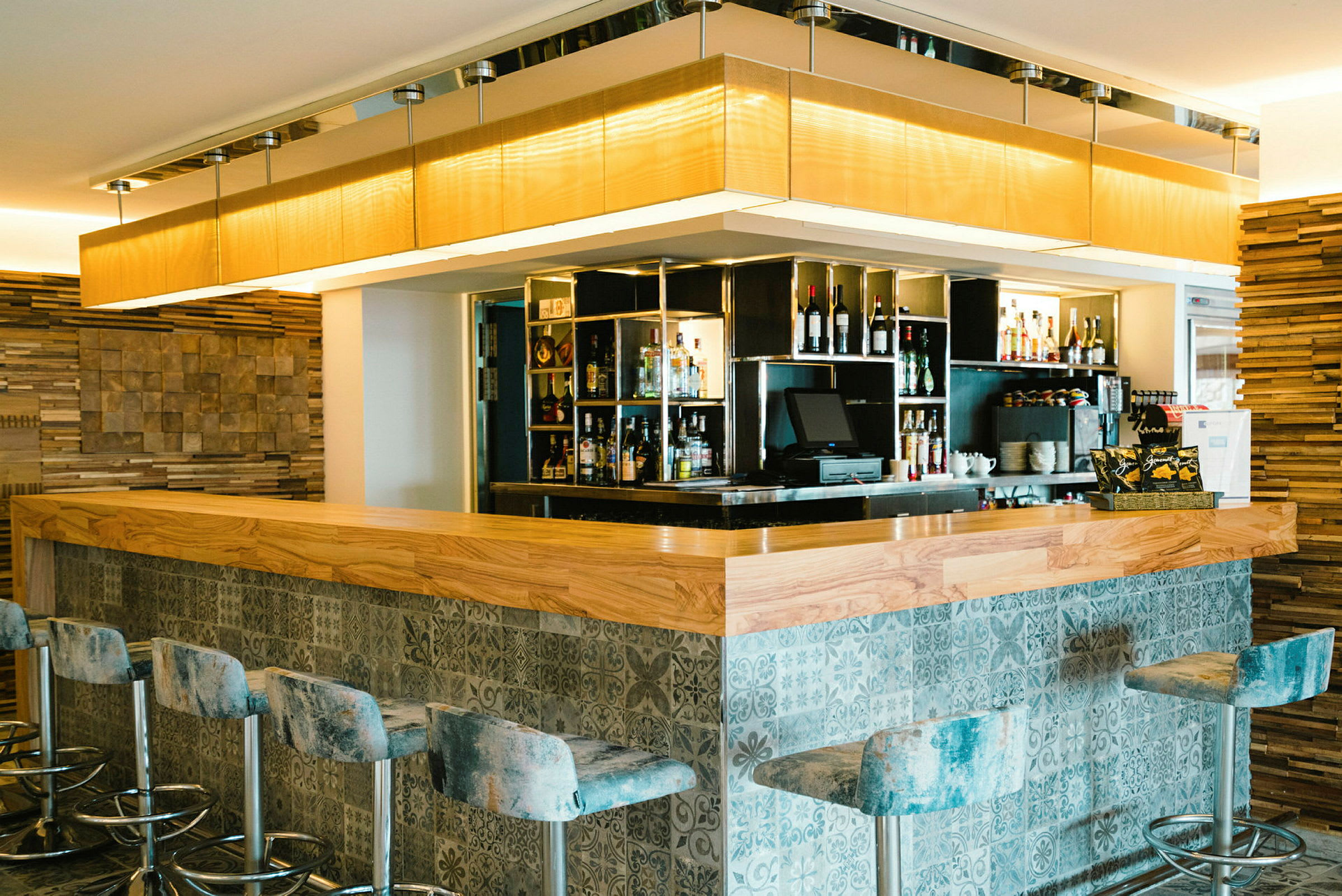 En bar med trädetaljer och designade stolar, samt hyllor med drycker. (AI-genererad text)