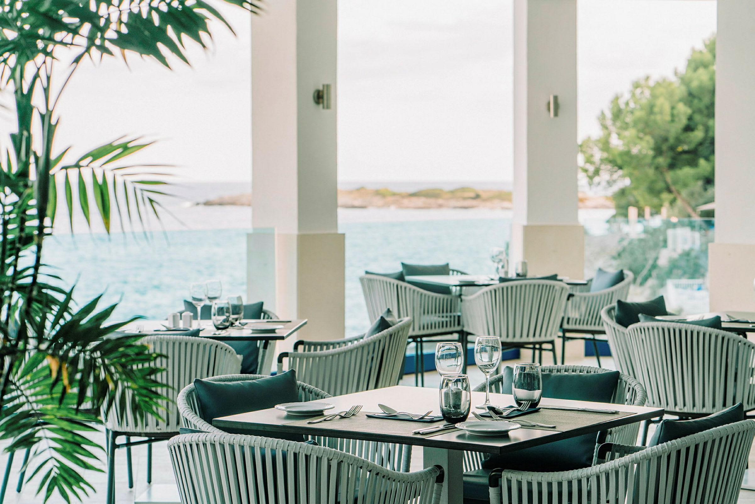 En utomhusrestaurang med utsikt över havet och vegetationen. (AI-genererad text)
