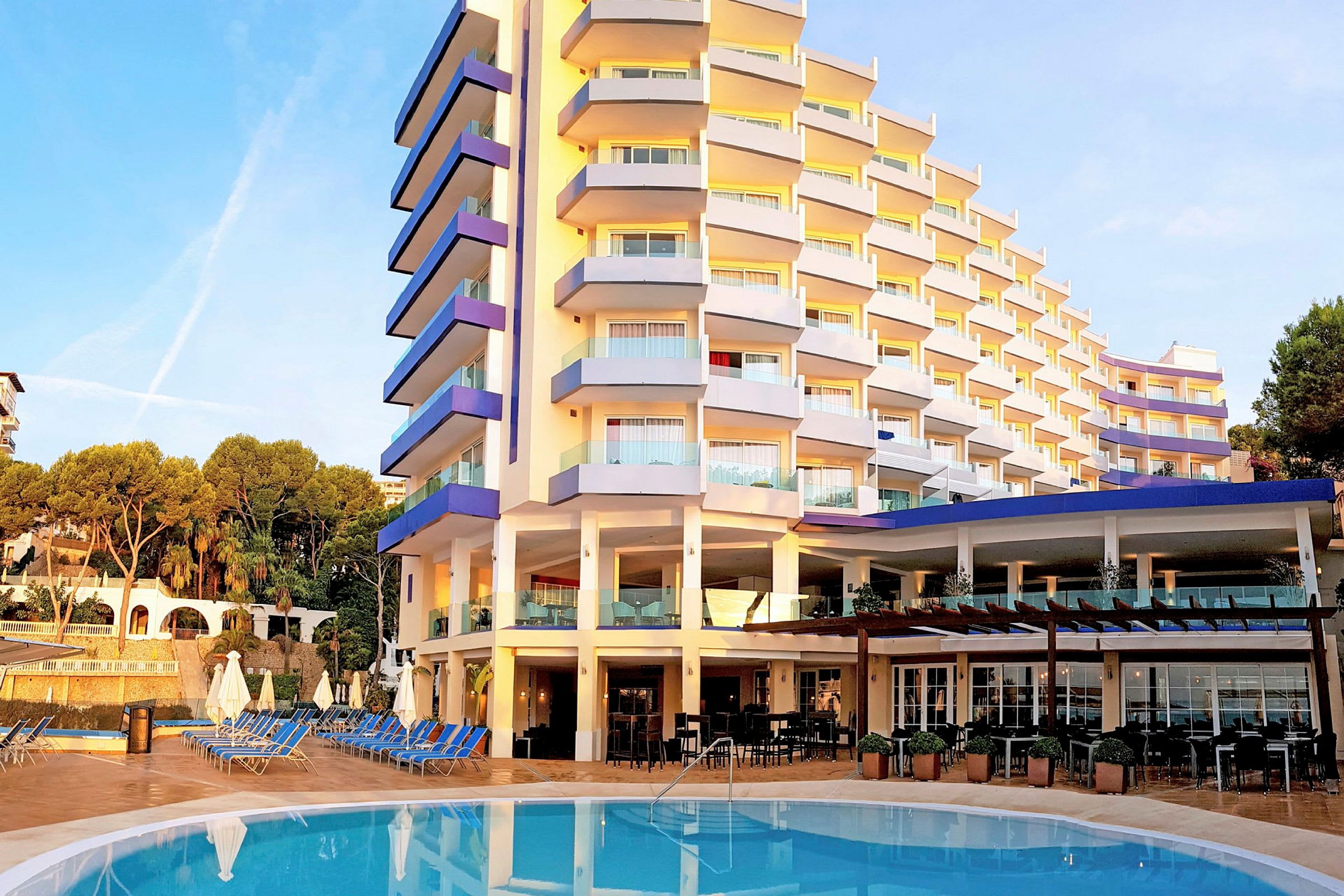 Ett hotell med en pool framför och solstolar runtom. (AI-genererad text)
