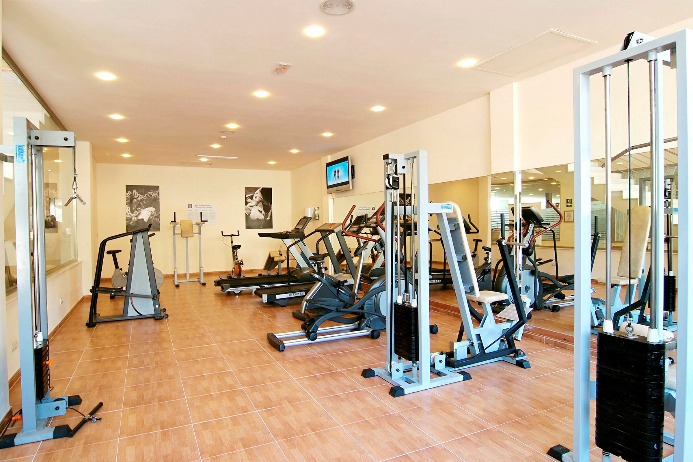 Ett ljust gym med olika träningsmaskiner och speglar på väggarna. (AI-genererad text)