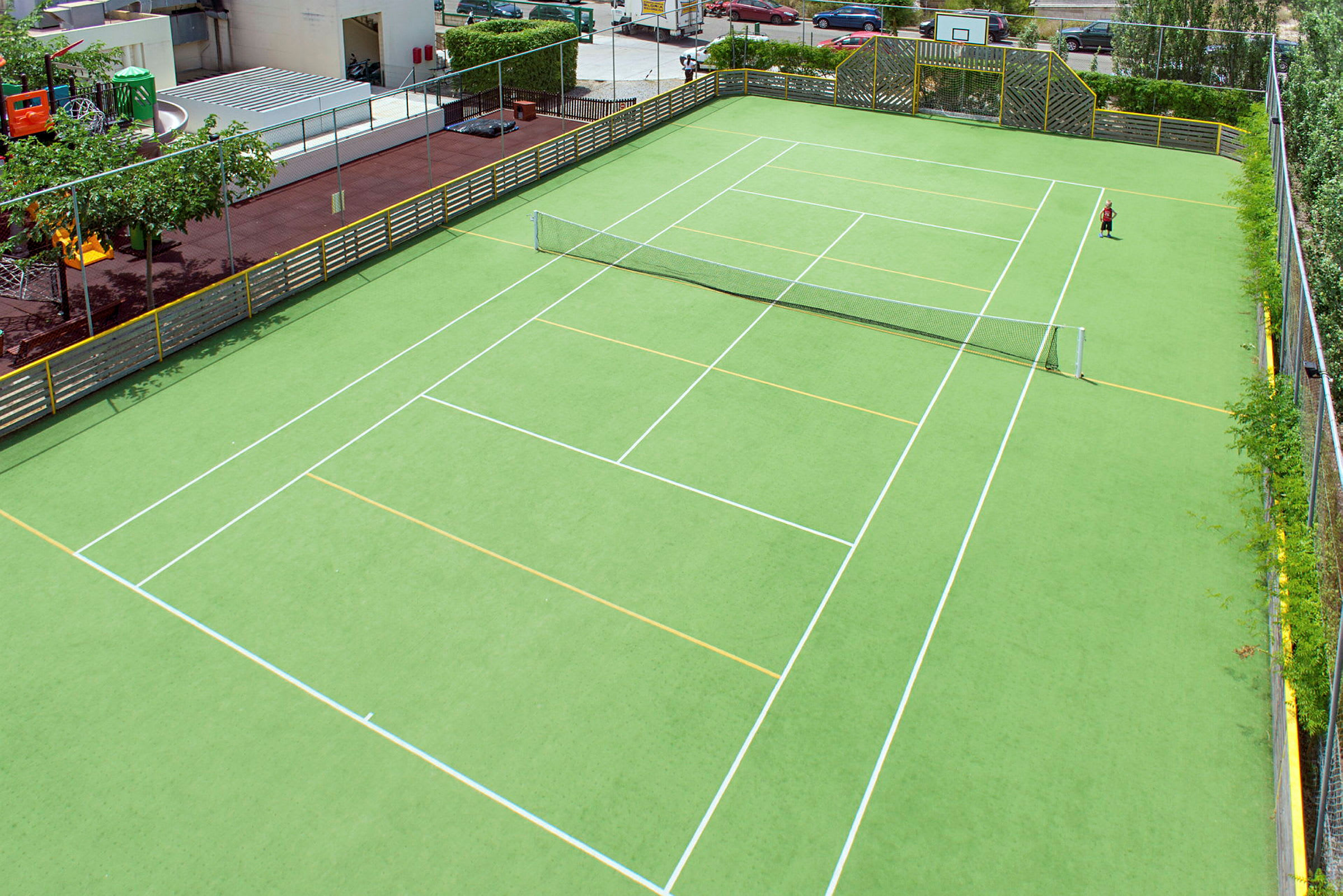 En tom tennisplan med grön konstgräs och ett nät i mitten. (AI-genererad text)