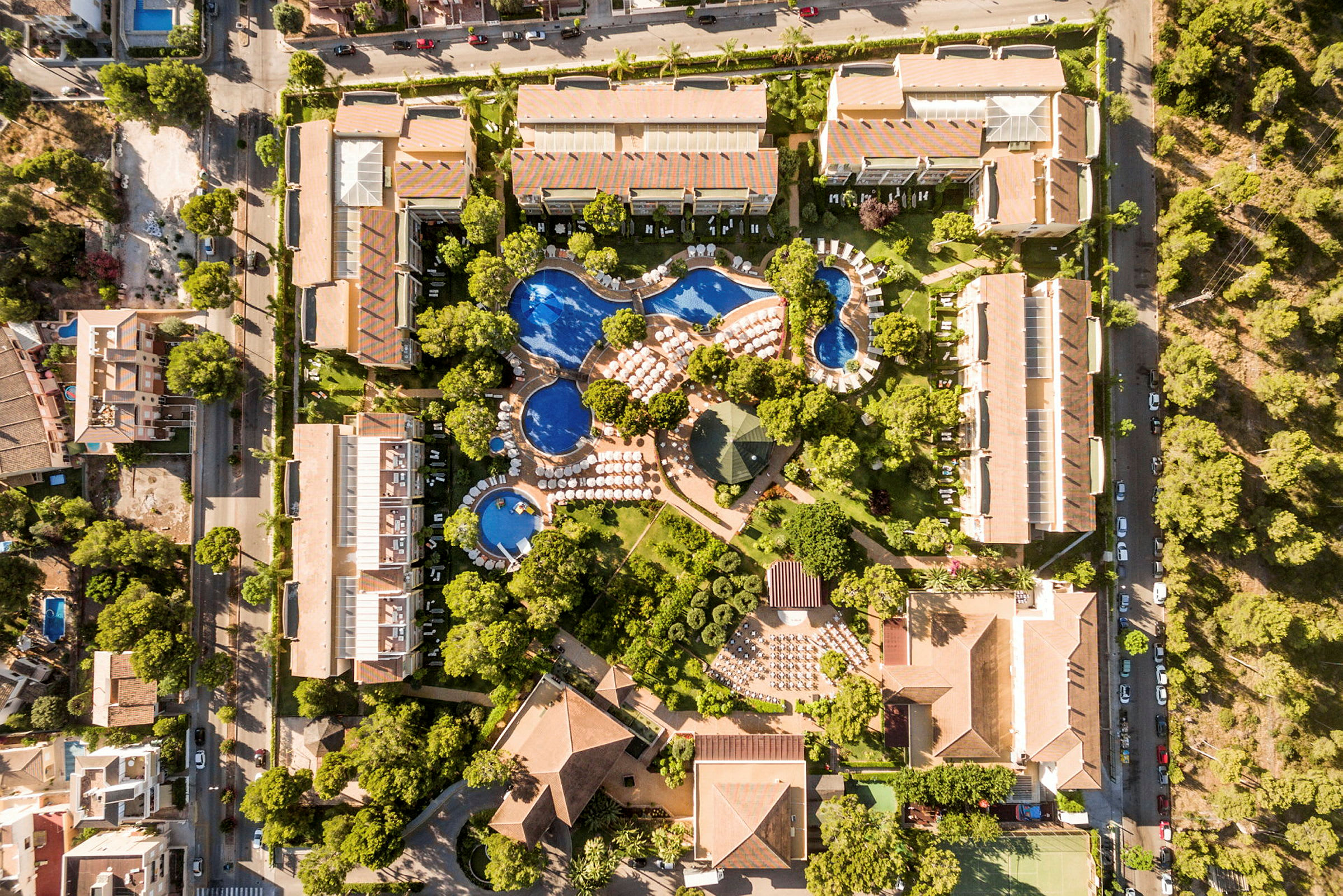 Flygfoto av en resort med pooler, gröna ytor och flervåningshus. (AI-genererad text)