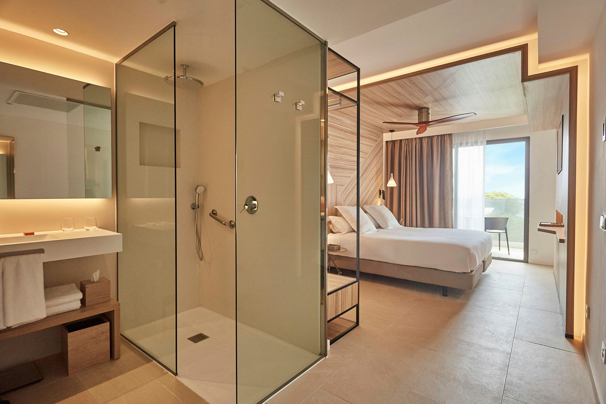 Ett modernt hotellrum med en glasdusch och ett sovområde med en dubbelsäng. (AI-genererad text)