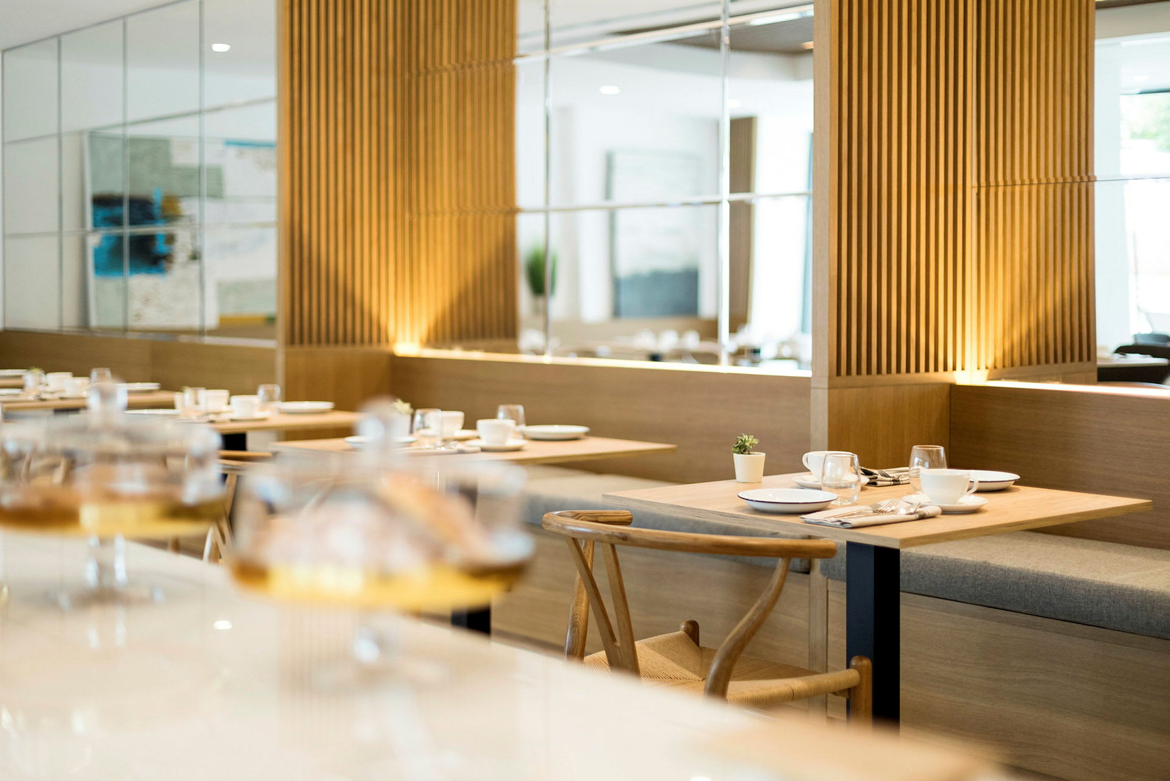 Restaurang med moderna möbler och träpaneler, dukade bord med porslin. (AI-genererad text)
